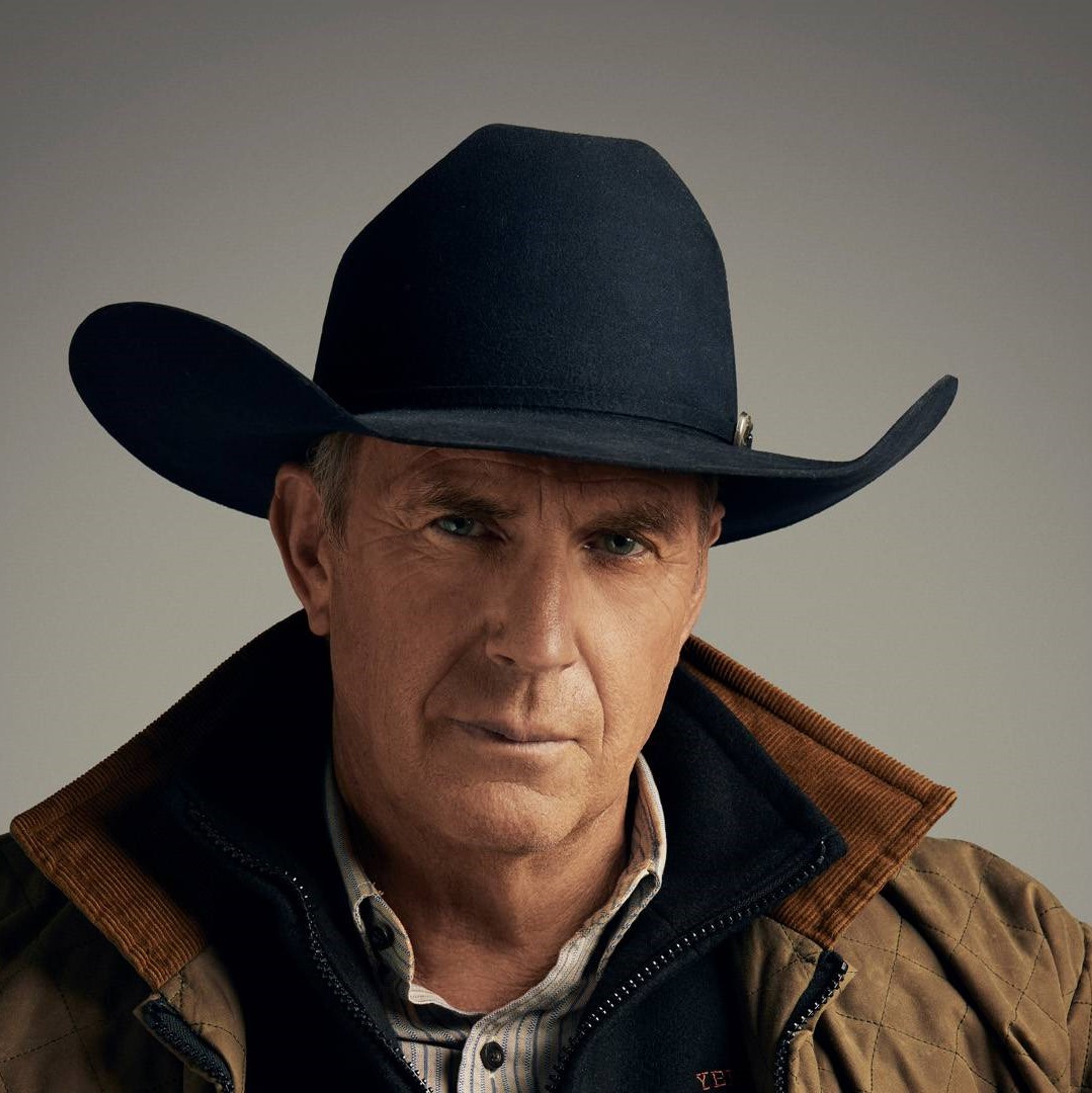 An older man with a weathered face wearing a cowboy hat and jacket