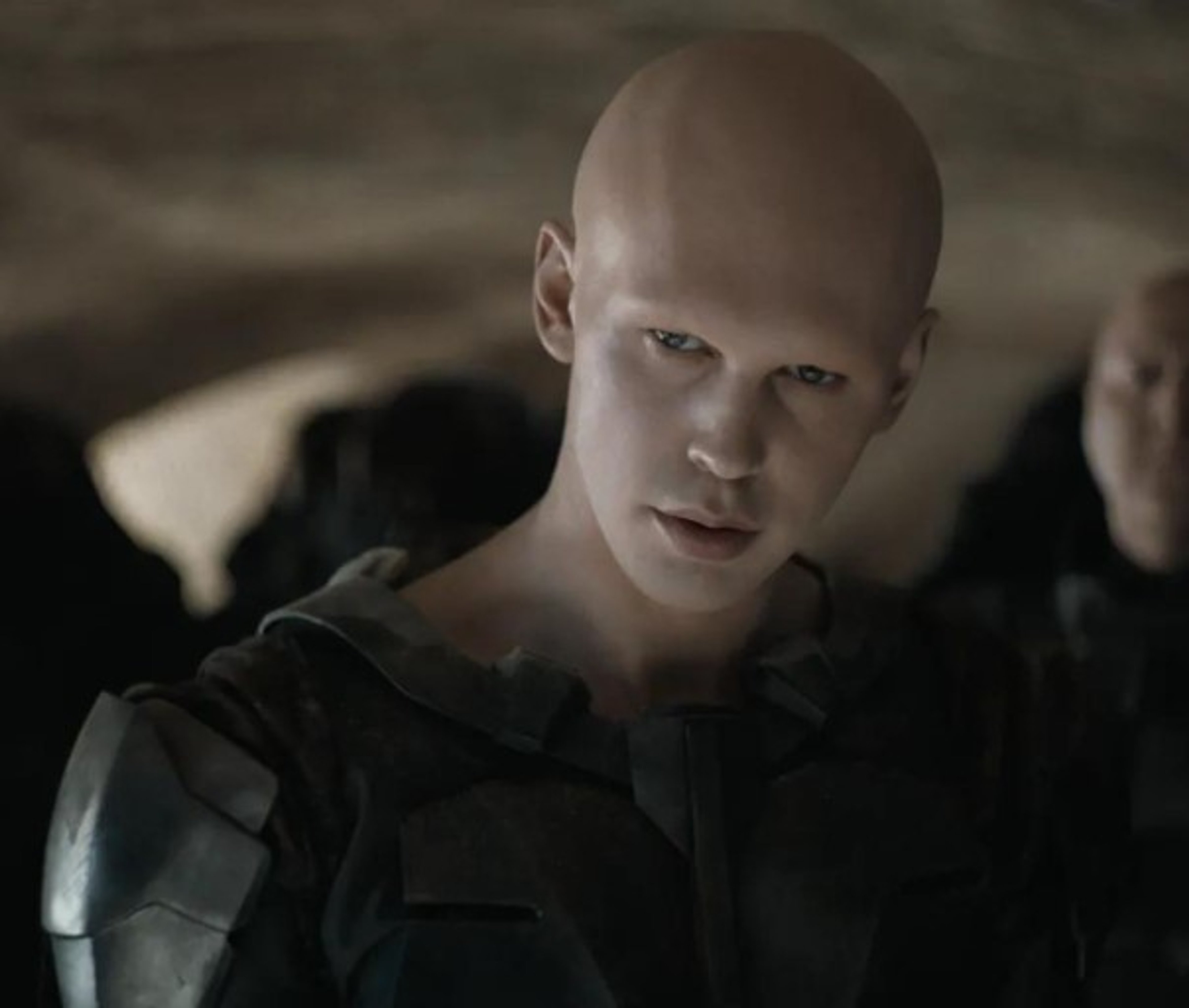 A bald, pale-skinned male character in a dark military uniform with an intense expression