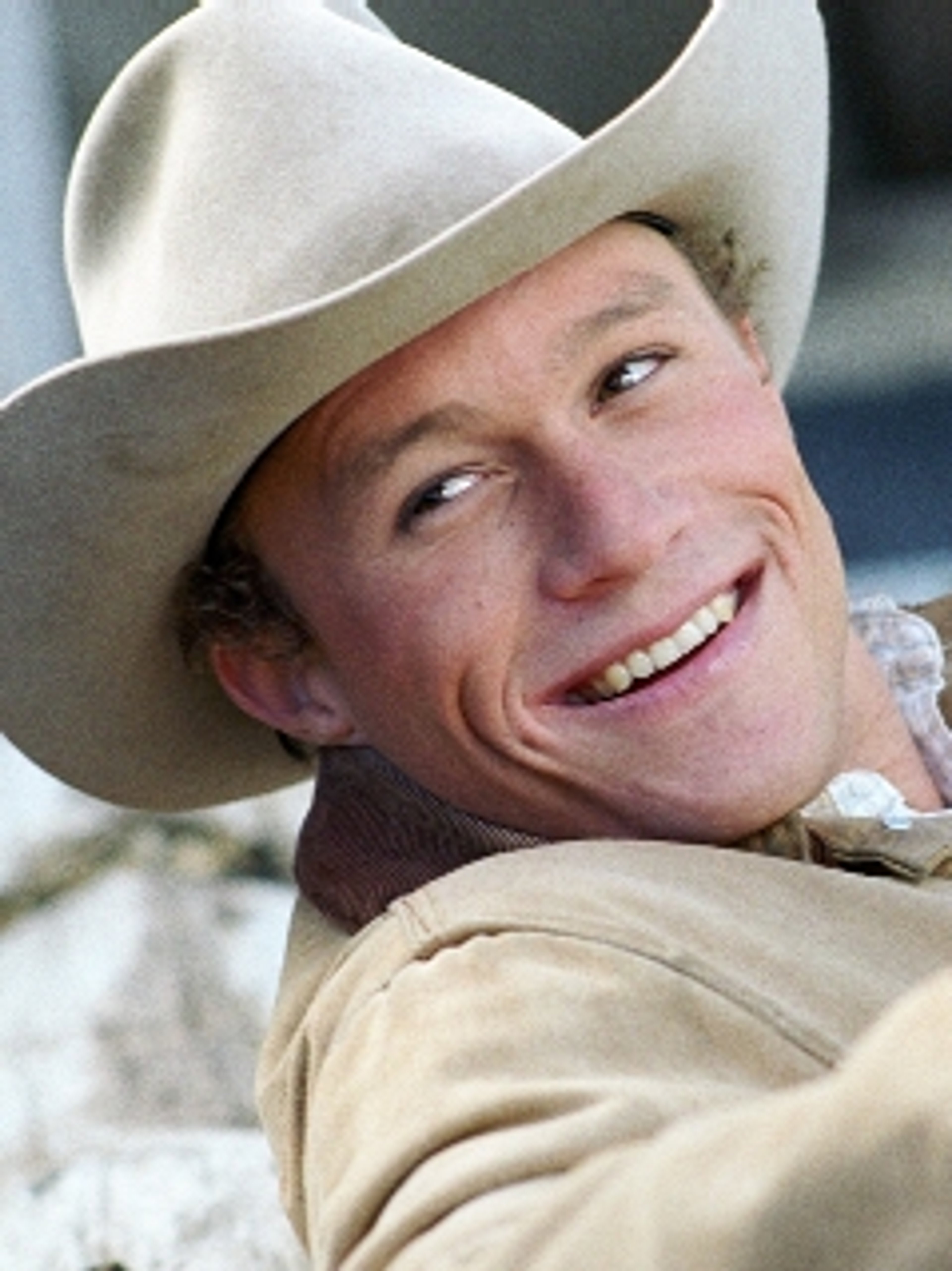 A smiling cowboy with a weathered face wearing a cowboy hat