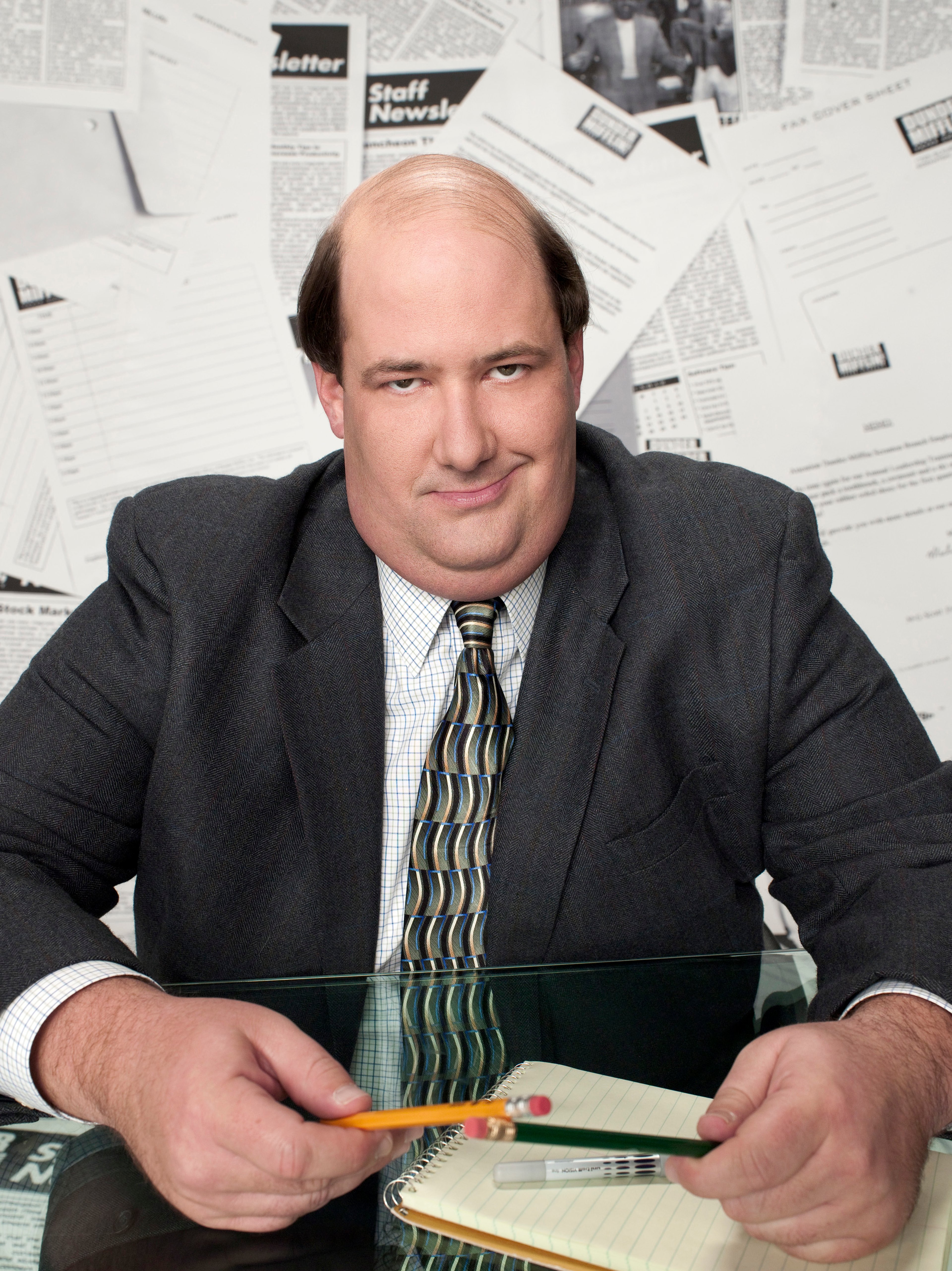 An overweight, middle-aged man in a suit sitting at an office desk