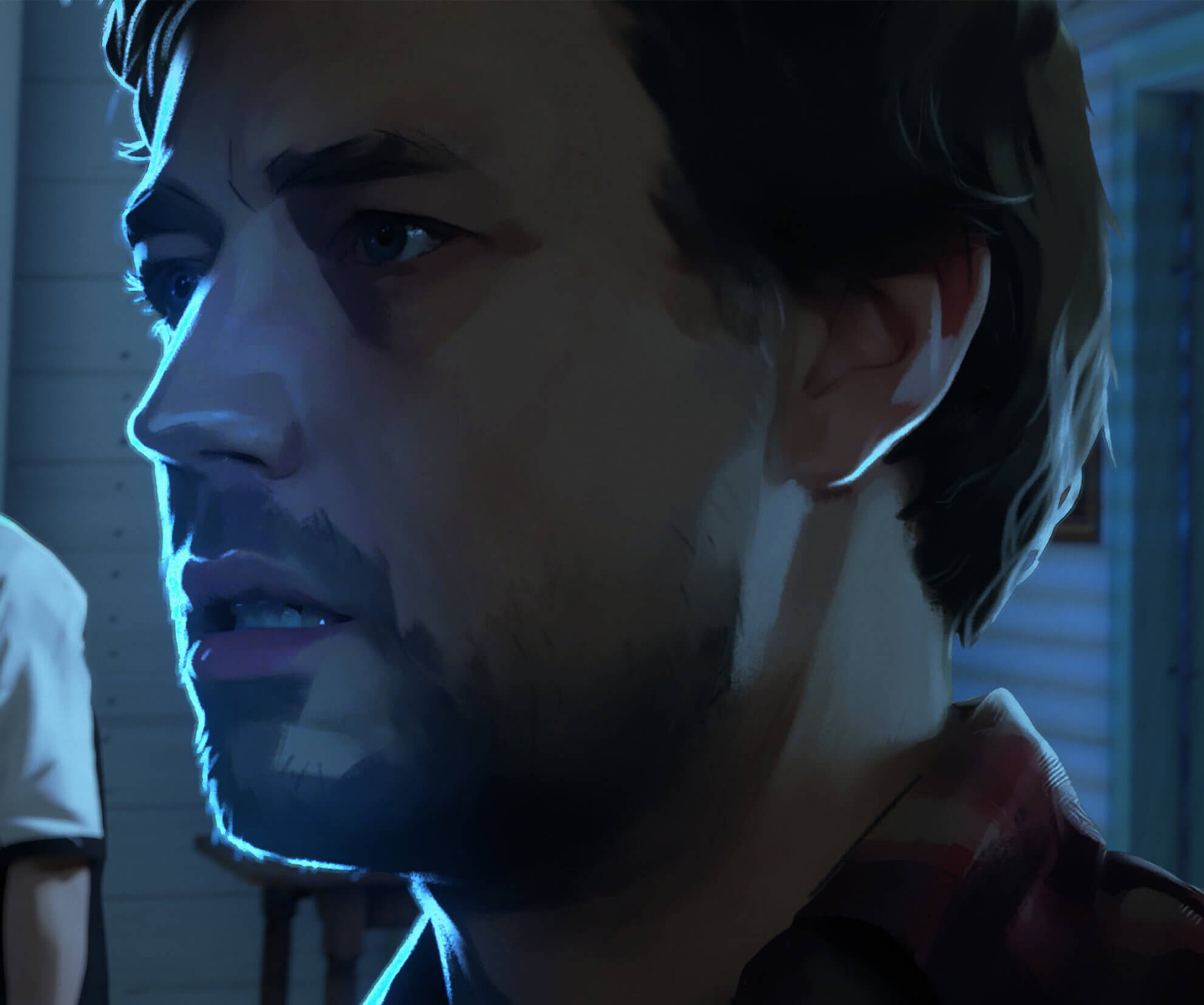 A close-up portrait of a young man with short, medium-brown hair and a distinctive facial features, wearing a red flannel shirt.