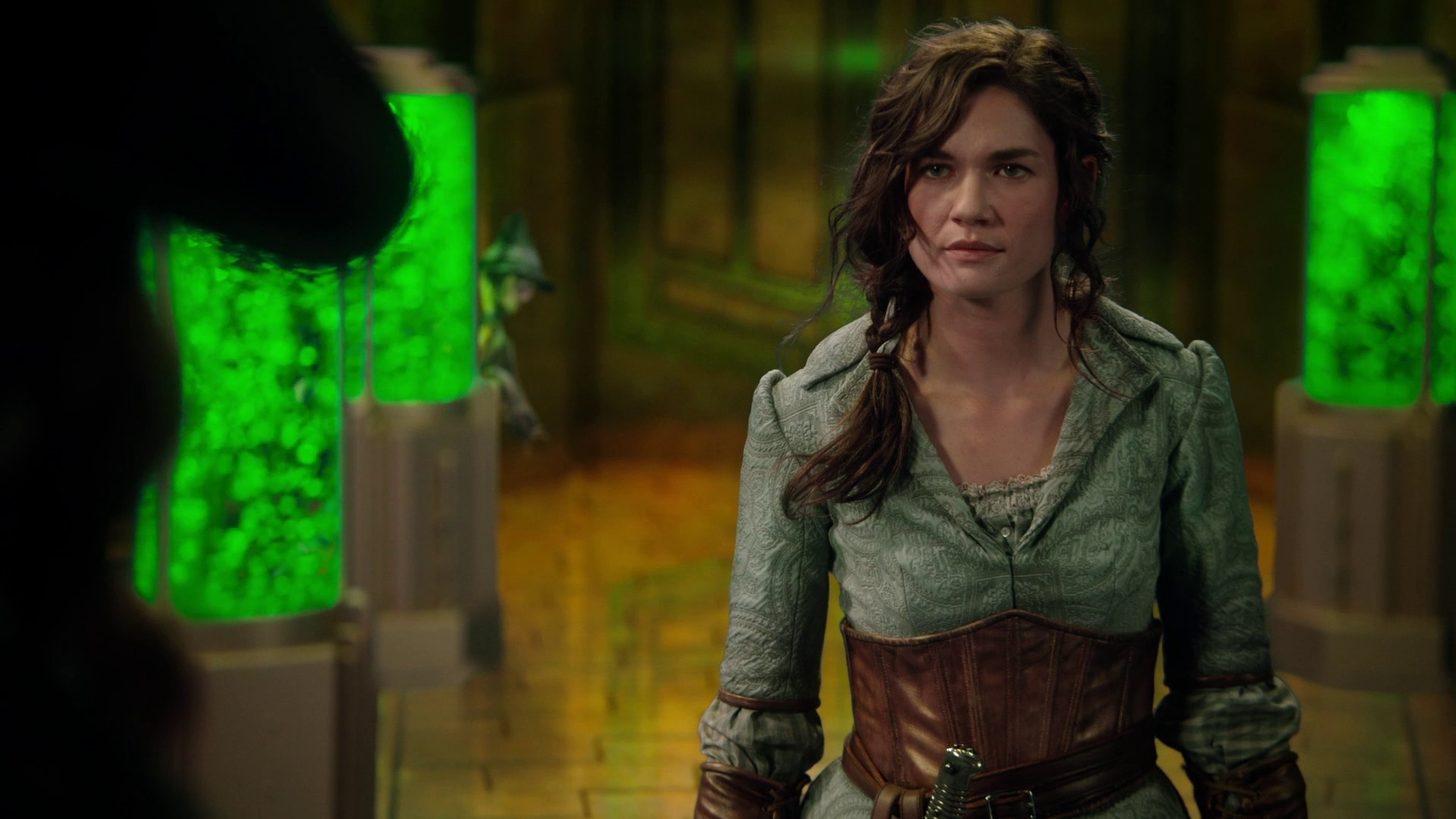 A young woman in a green dress standing in a forest