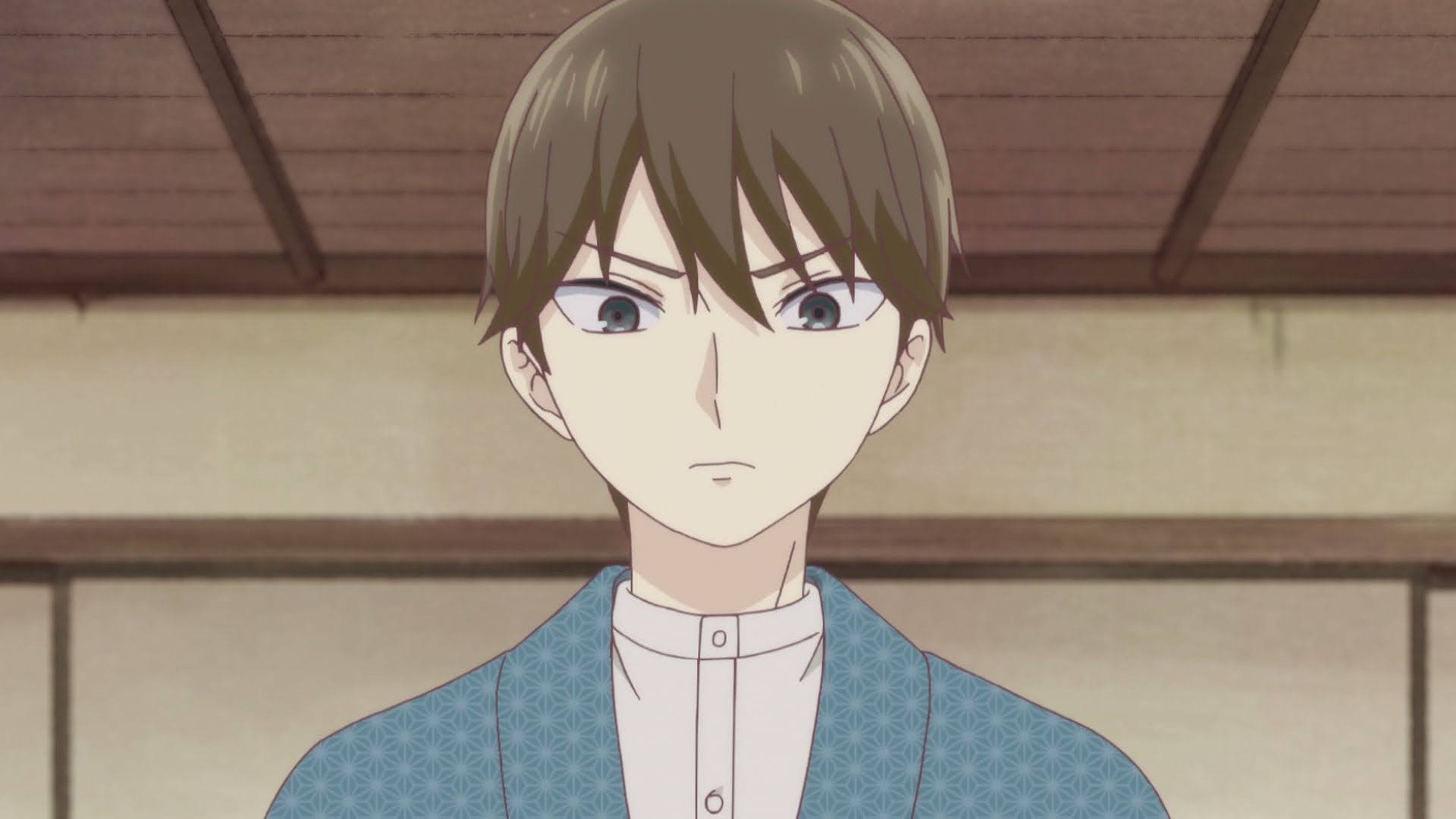 A young man with light brown hair and grey eyes wearing a blue and white checkered shirt