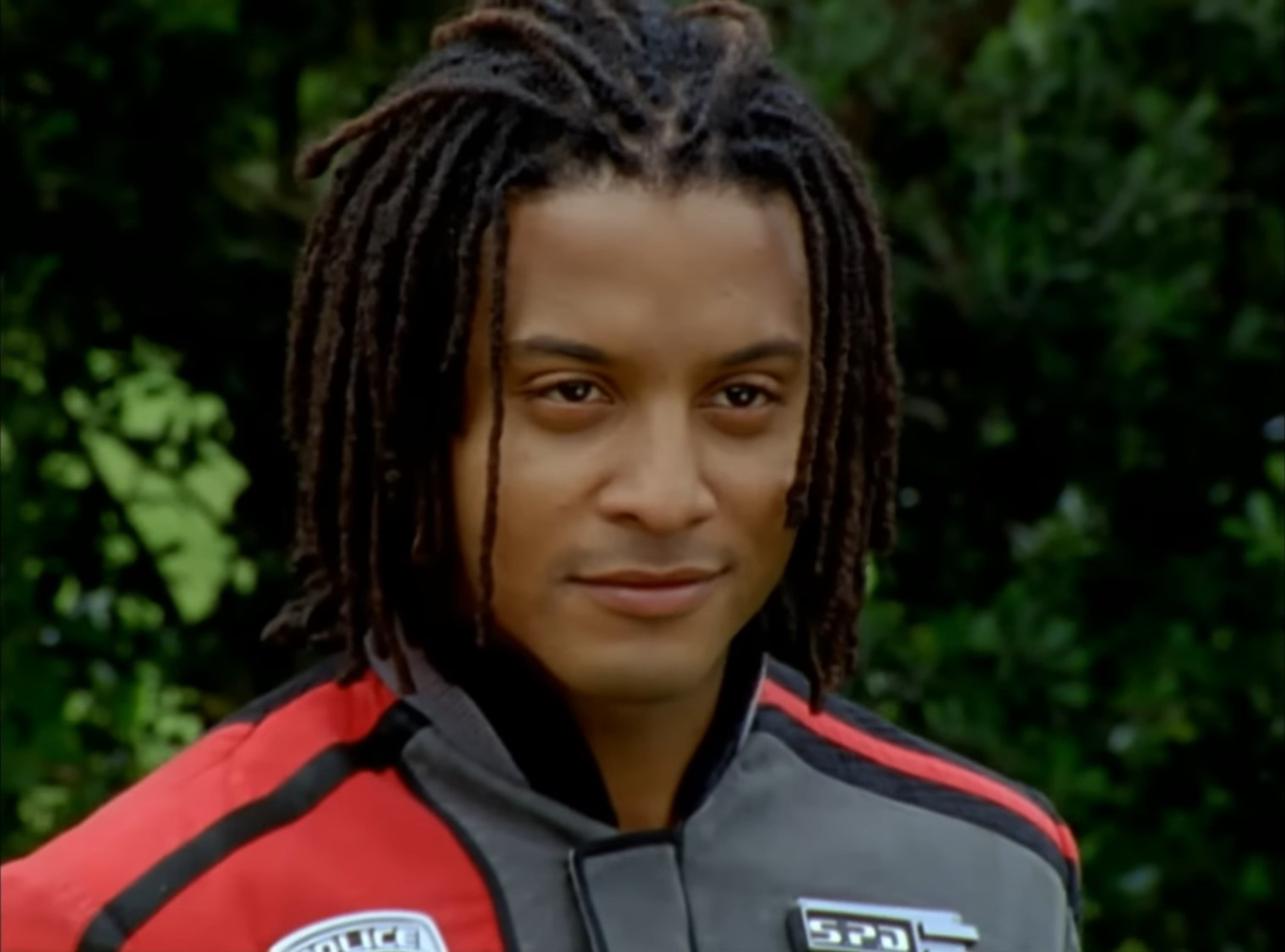 A man with dreadlocks wearing a red jacket