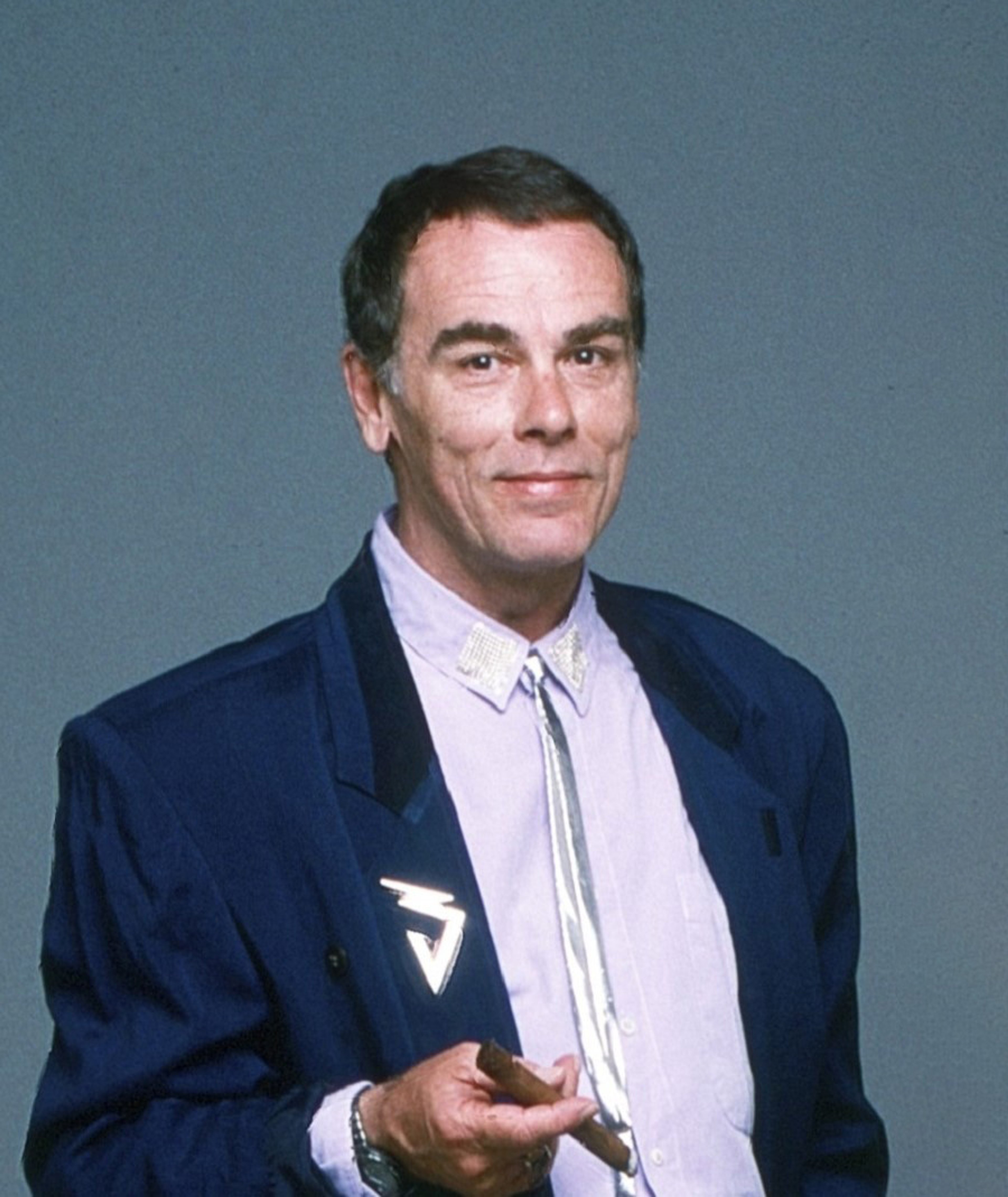 A middle-aged man in a navy blue suit with a serious expression