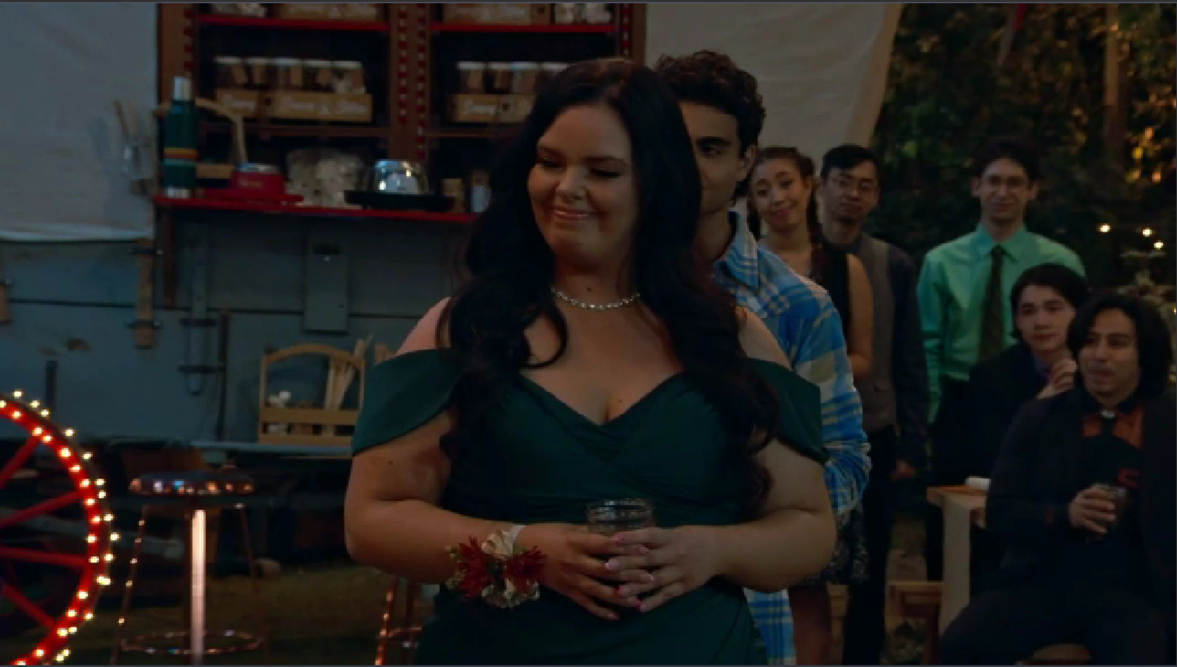 A young woman with long dark hair wearing a green tank top in an outdoor camp setting