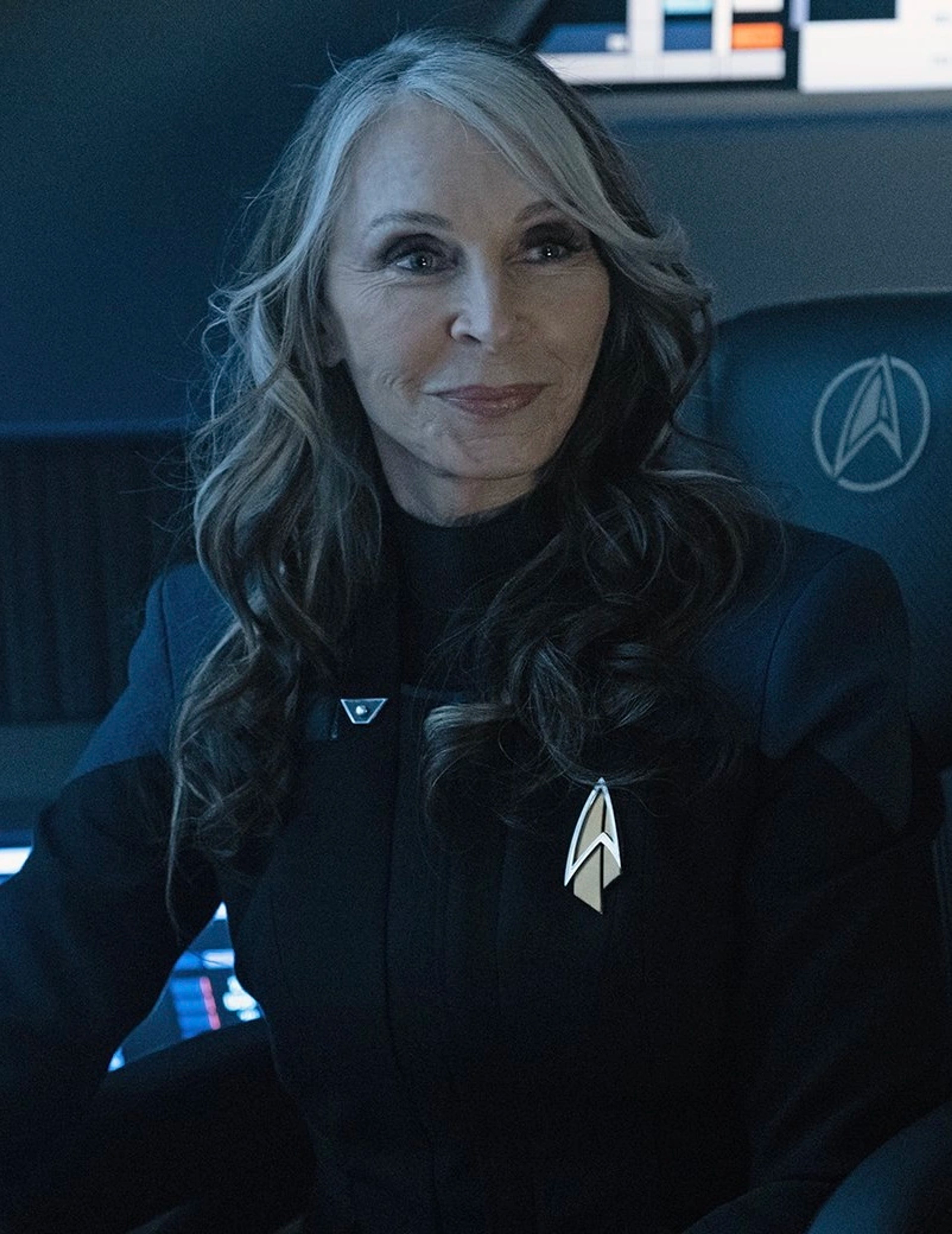 A woman in a Starfleet uniform with long, wavy brown hair