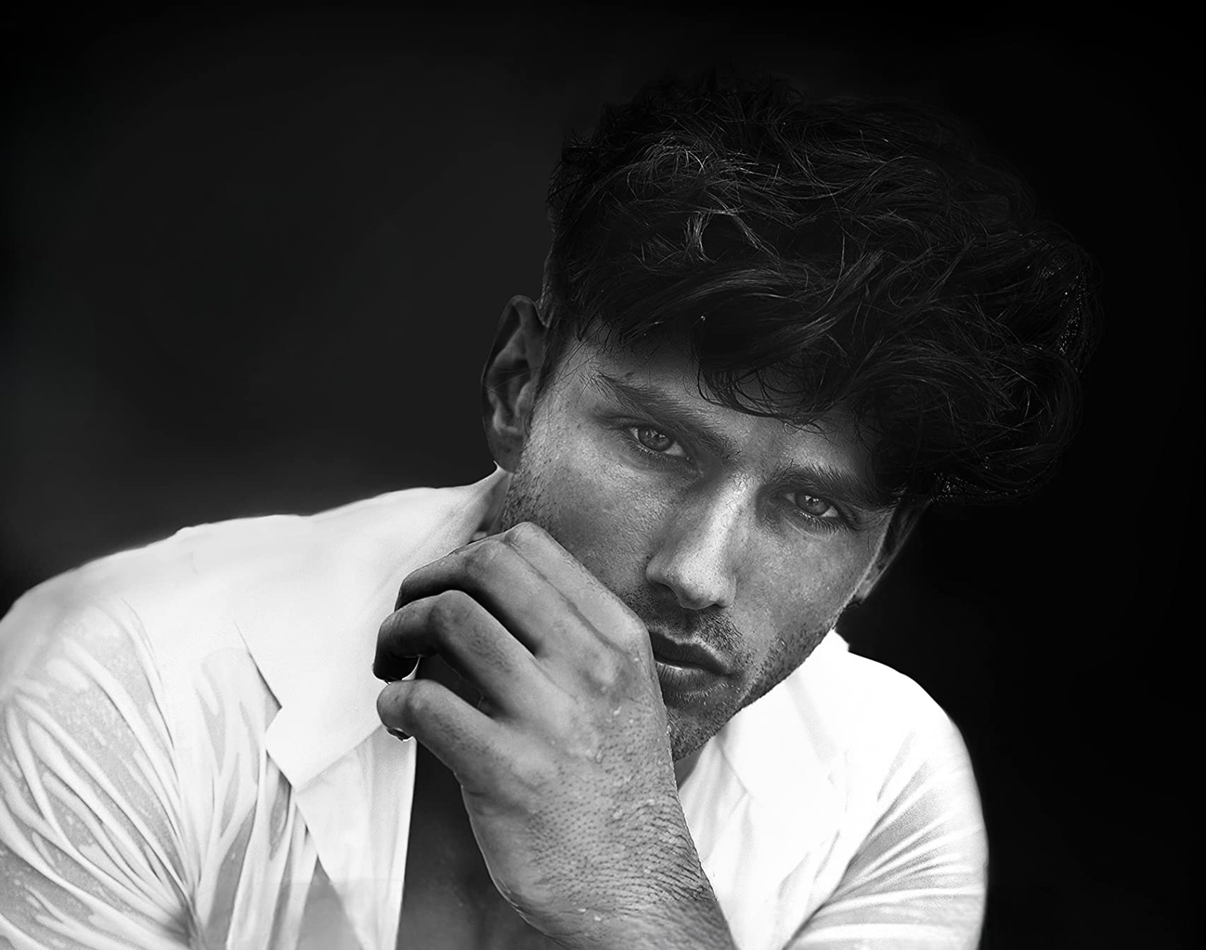 A close-up portrait of a serious-looking man in a white shirt