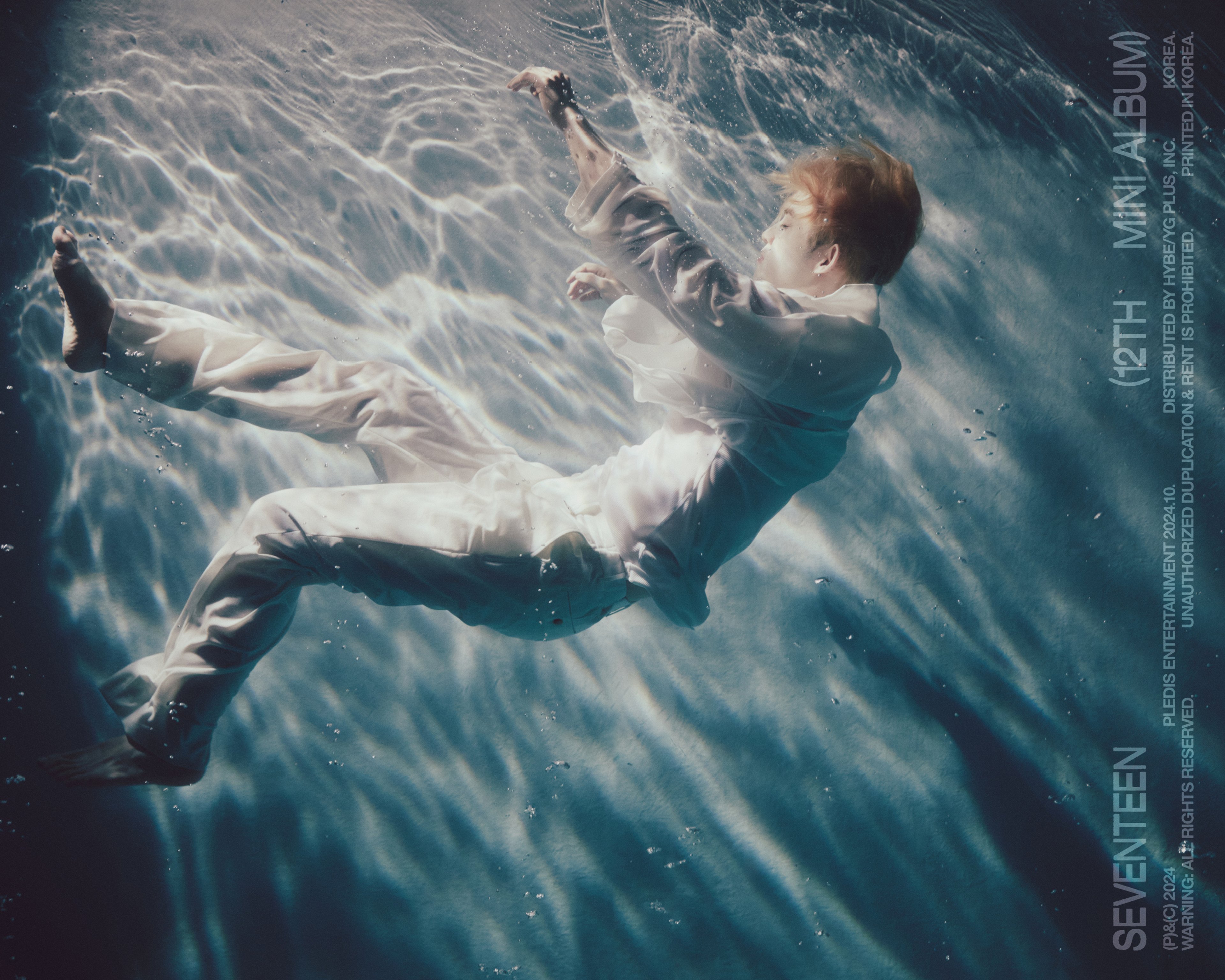 A person floating underwater in a white, flowing garment