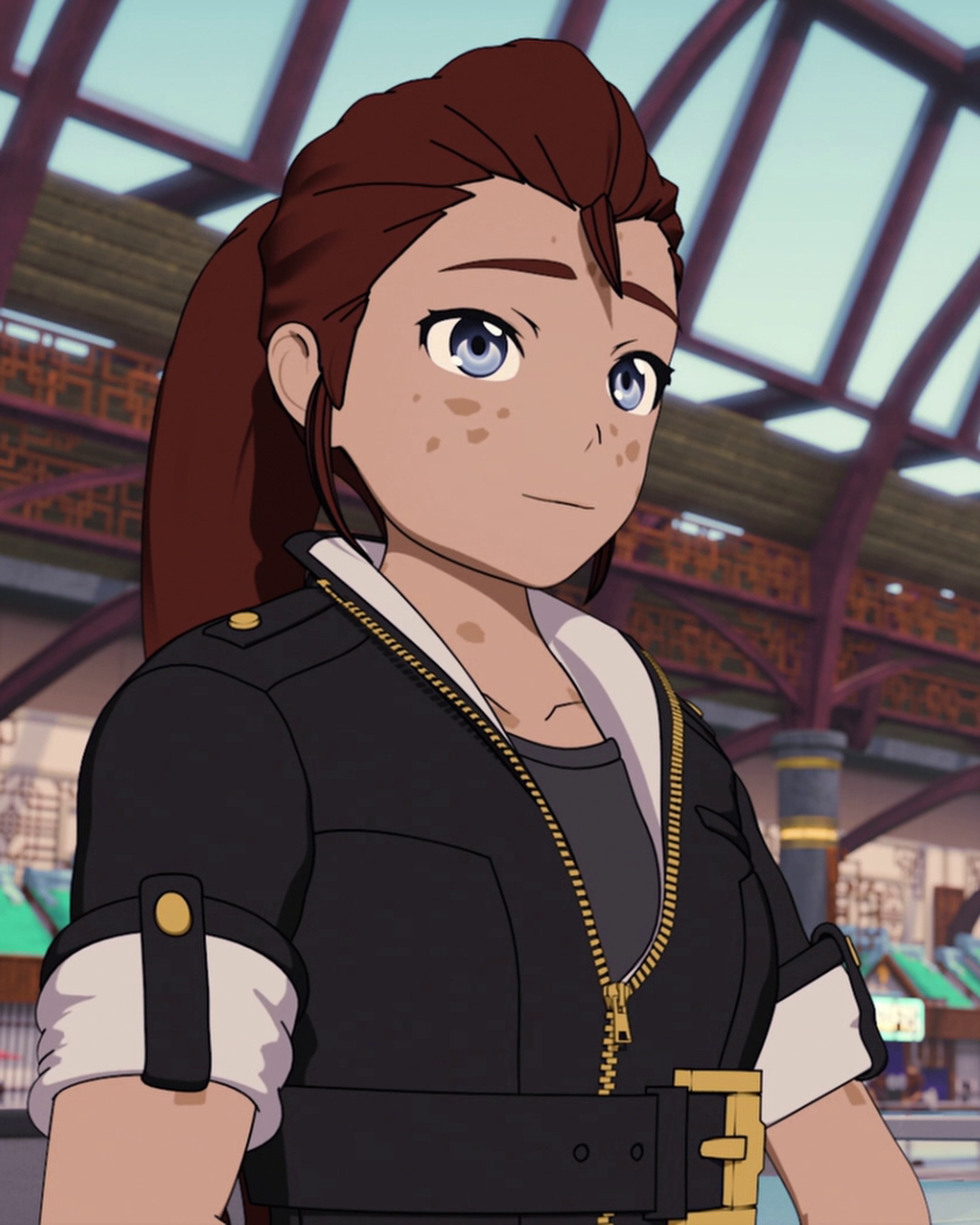 A young woman with brown hair and blue eyes wearing a black jacket with gold accents.