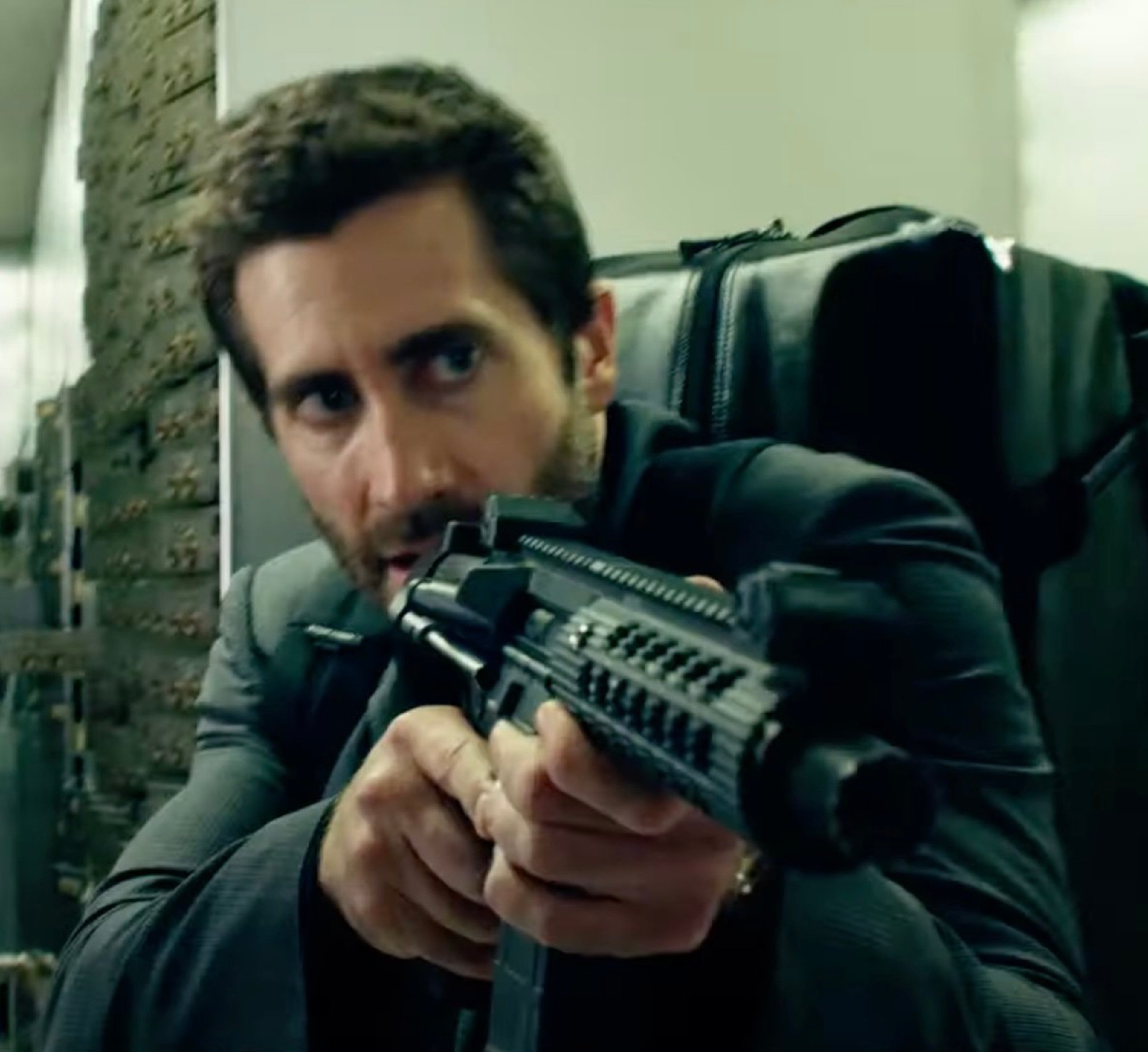 A man holding a firearm in a tense, action-oriented setting.