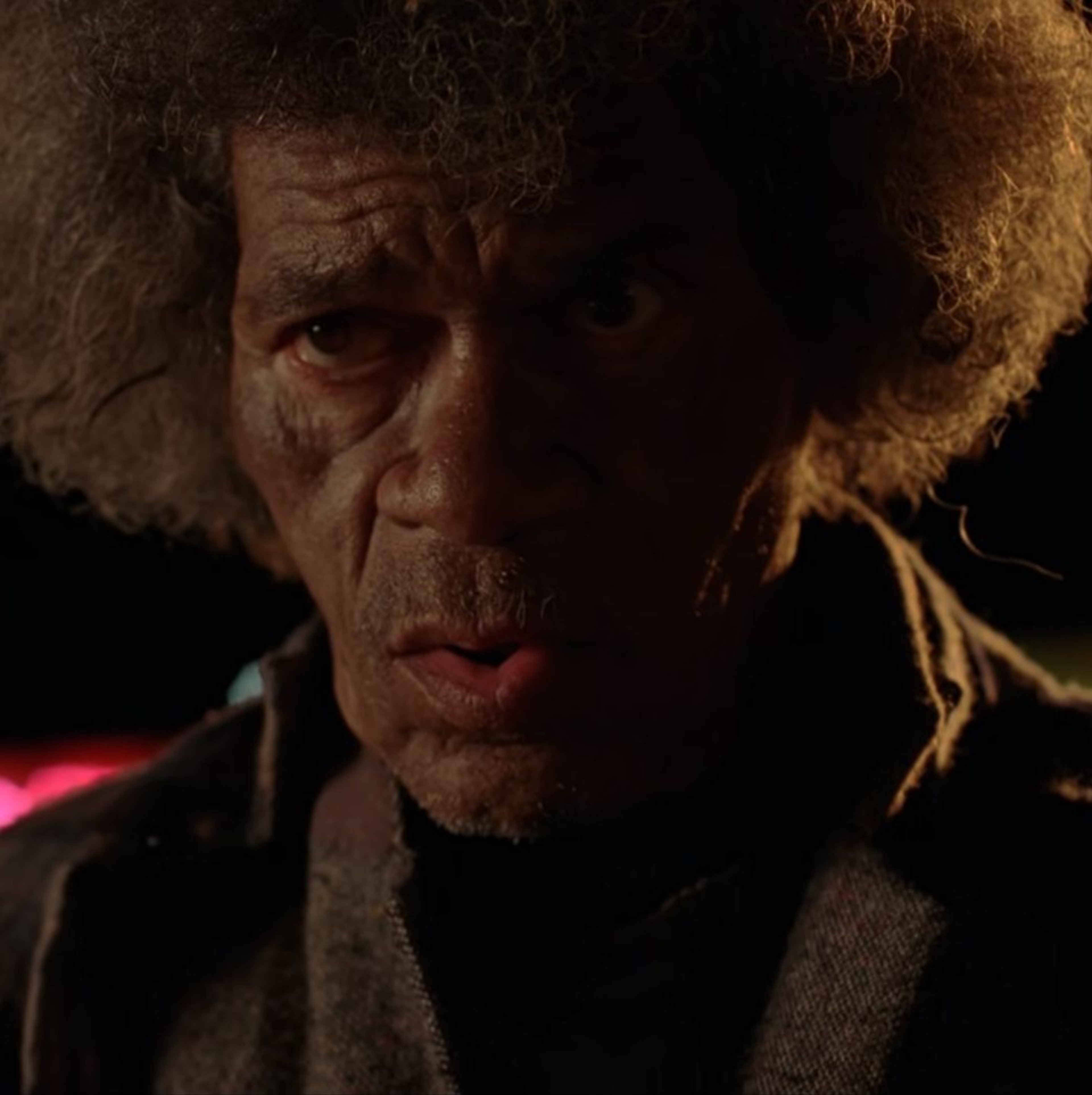 An older homeless man with a long beard and disheveled appearance