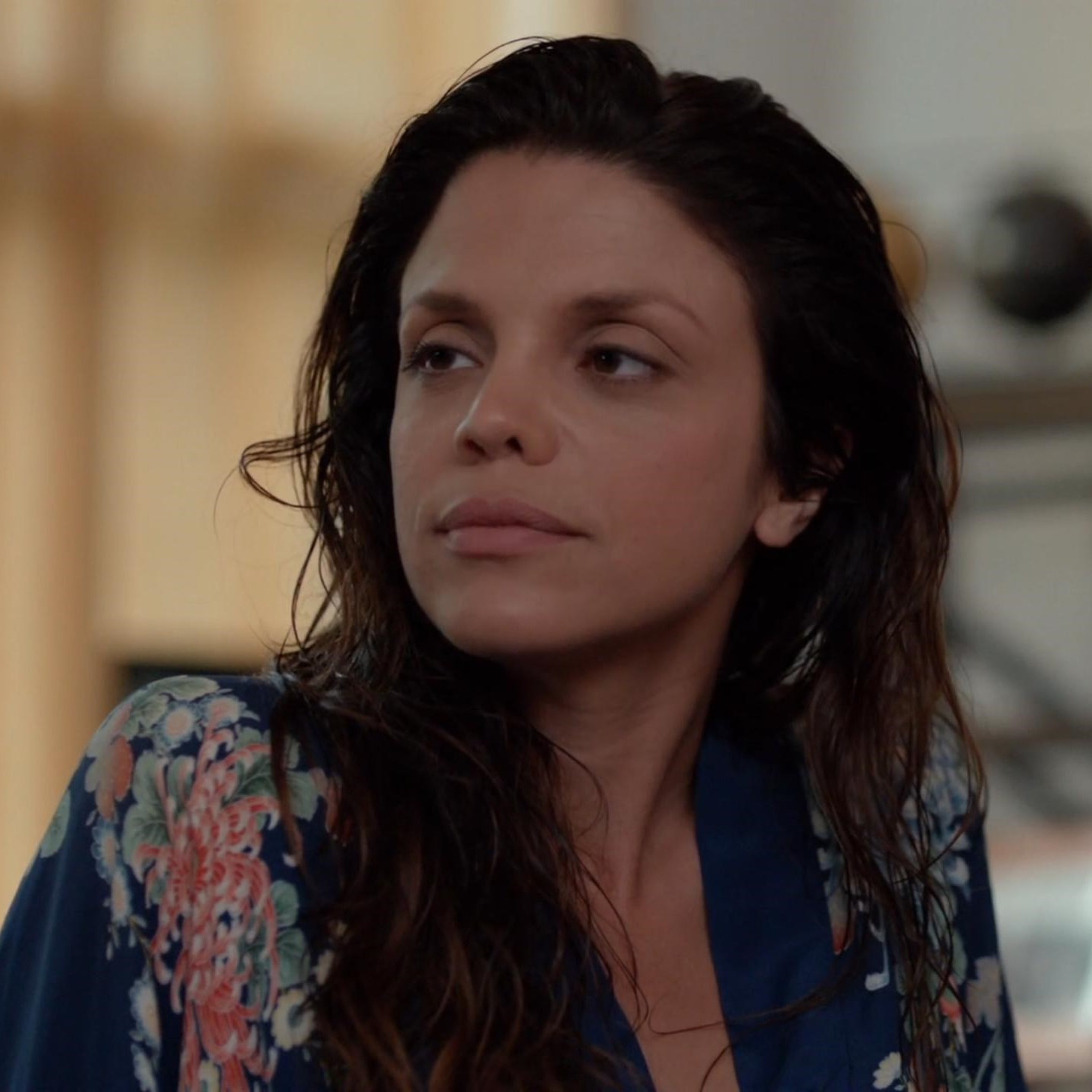 A woman with dark hair wearing a patterned shirt