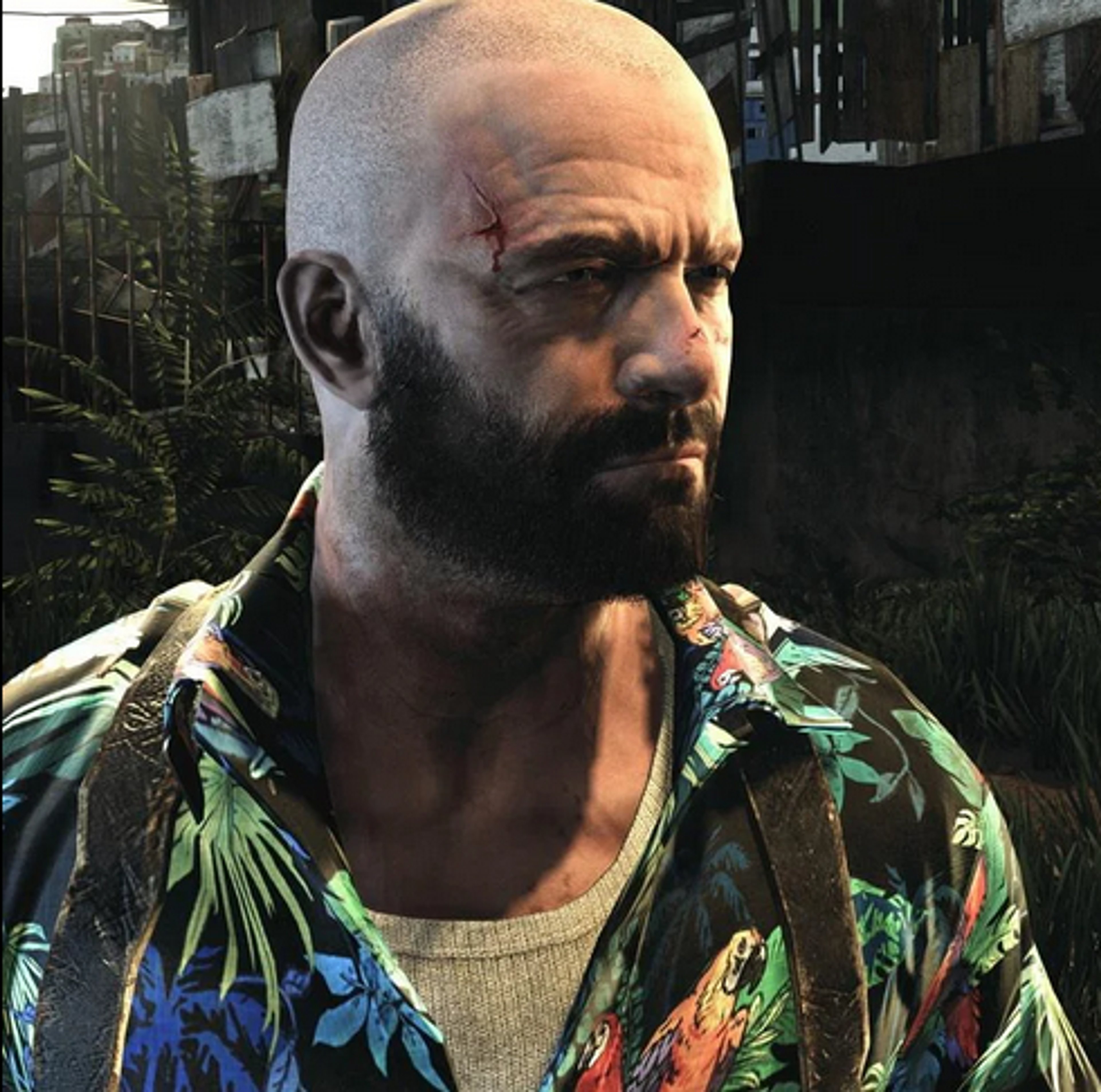 A bald, bearded man with a serious expression wearing a tropical shirt