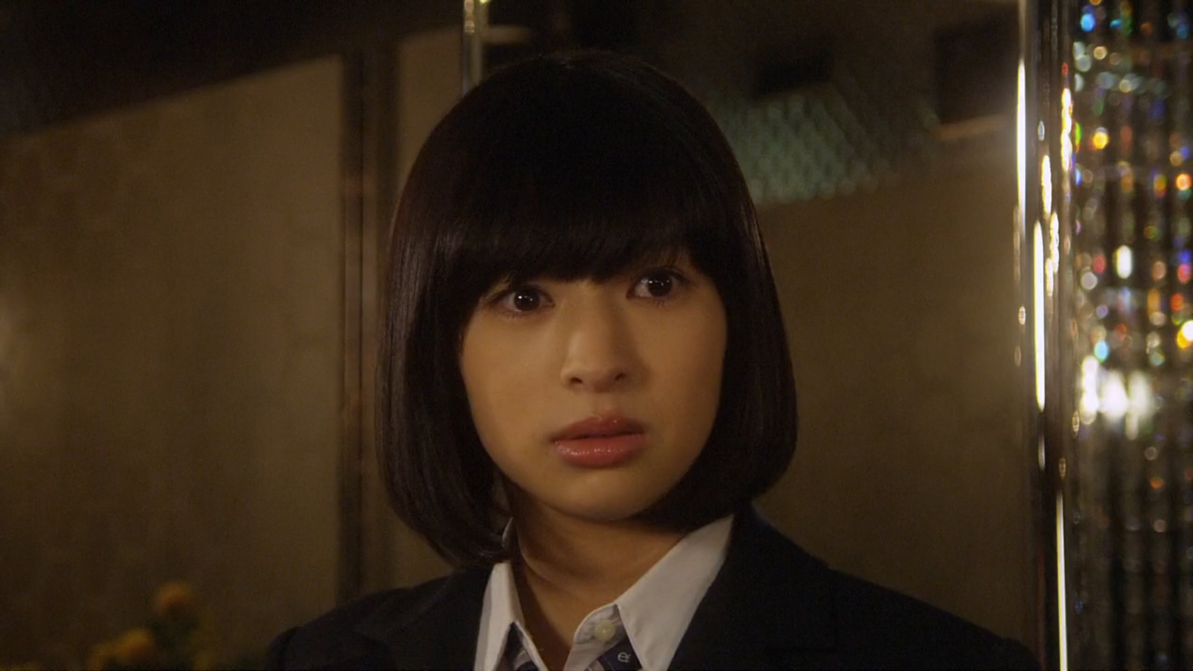 A young woman in a school uniform with a serious expression