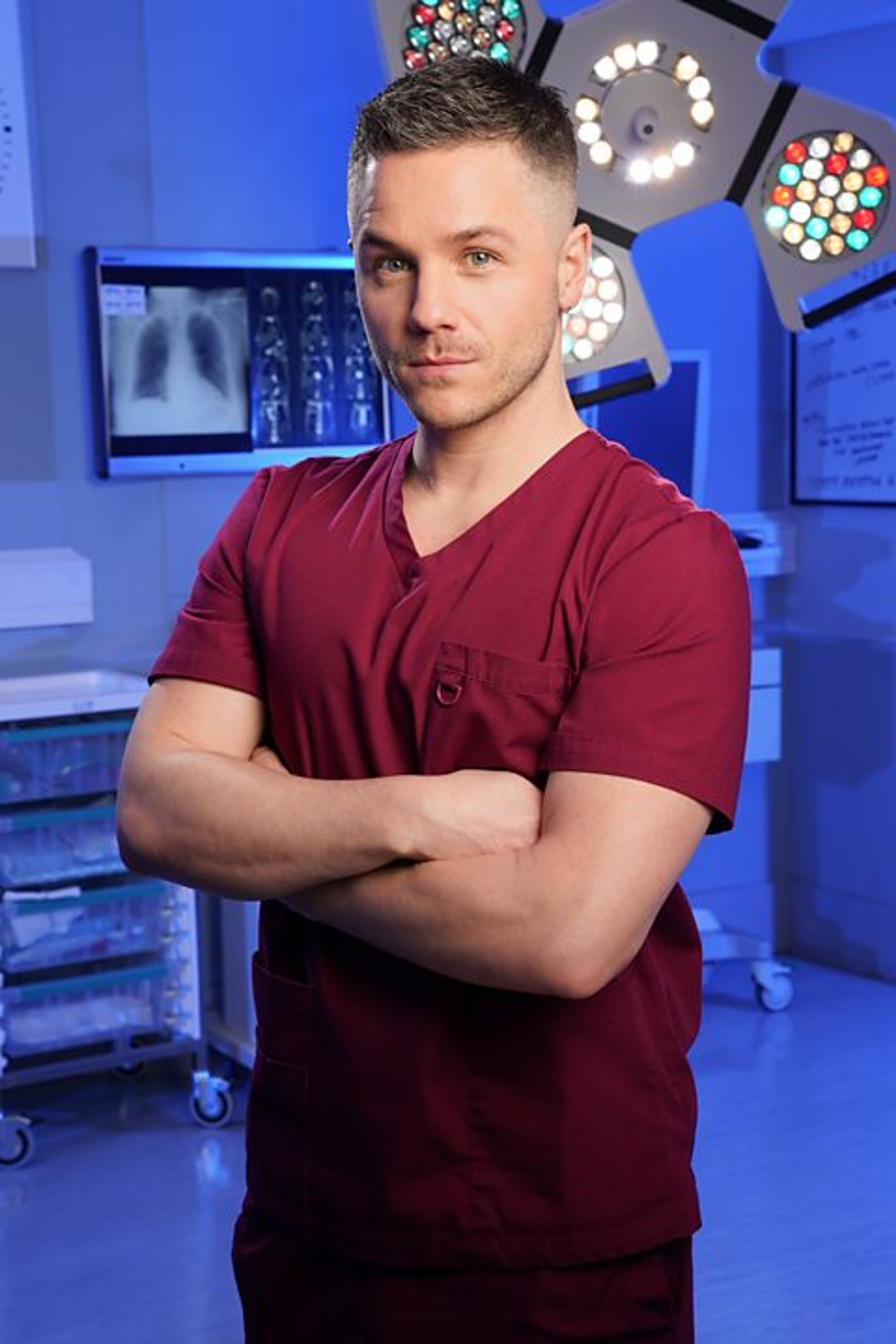 A man in a red scrub top standing in a medical setting