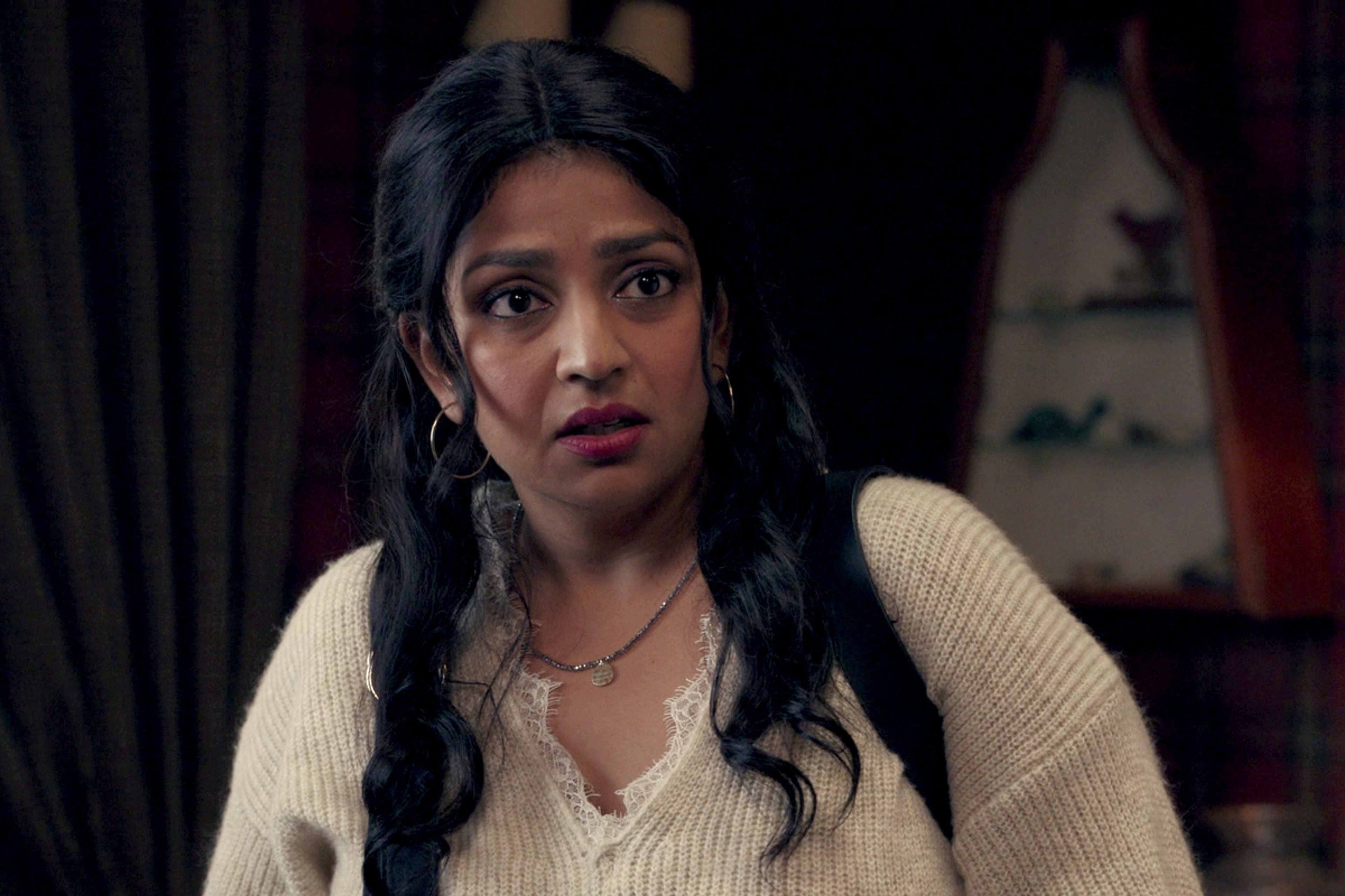 A young woman with long dark hair wearing a cream-colored sweater