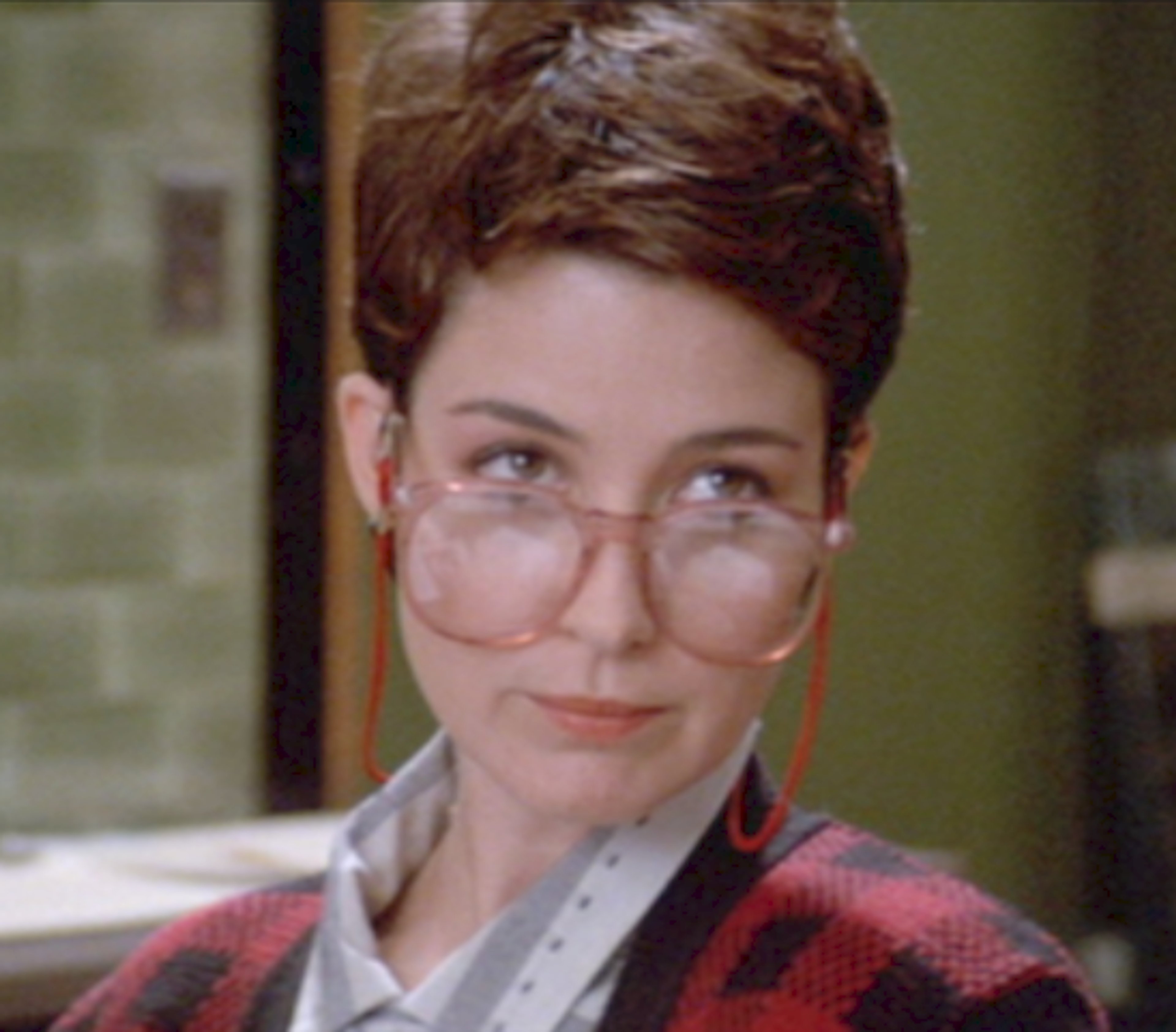 A woman with short brown hair and glasses wearing a red sweater