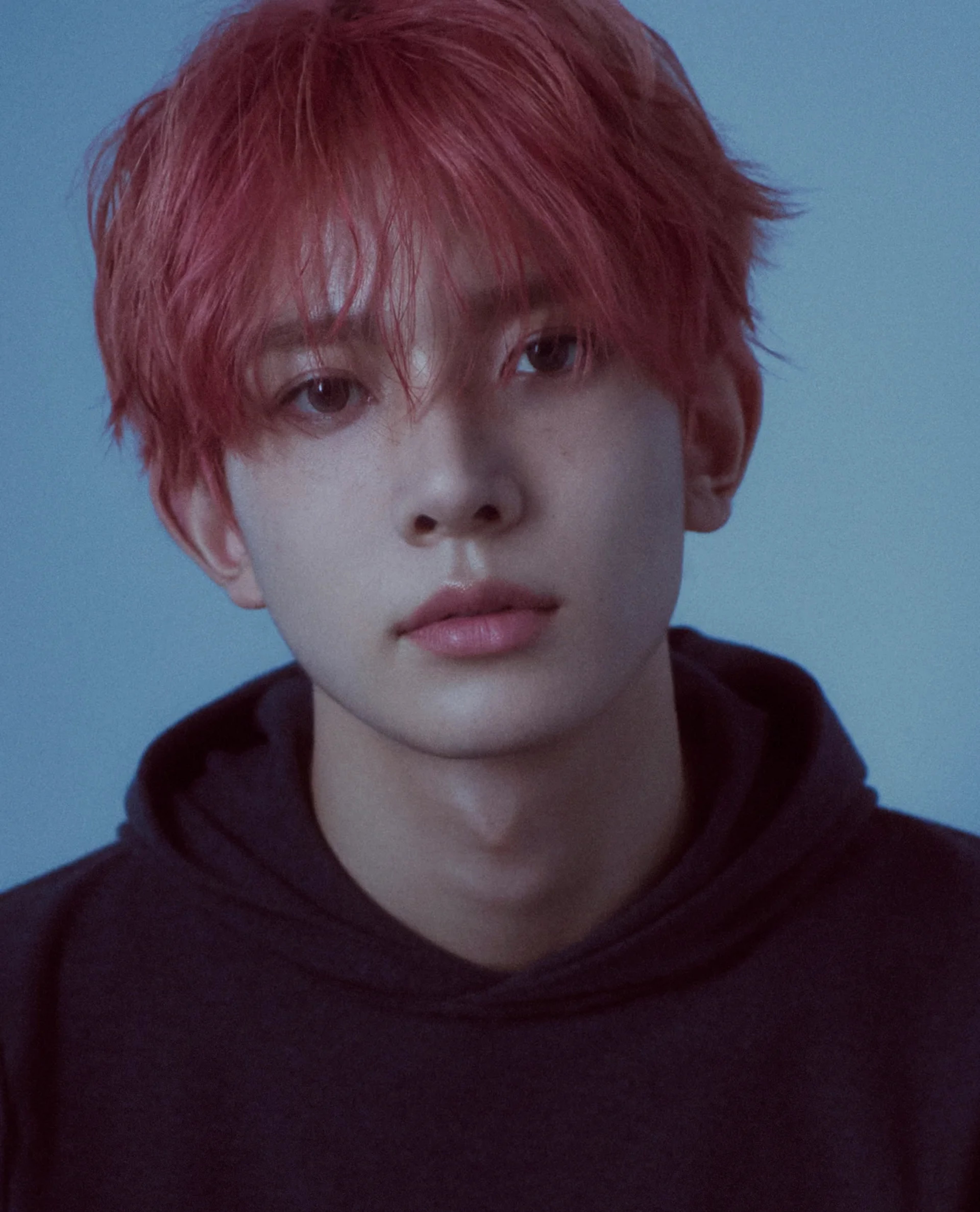 A young man with reddish-pink hair wearing a black turtleneck sweater