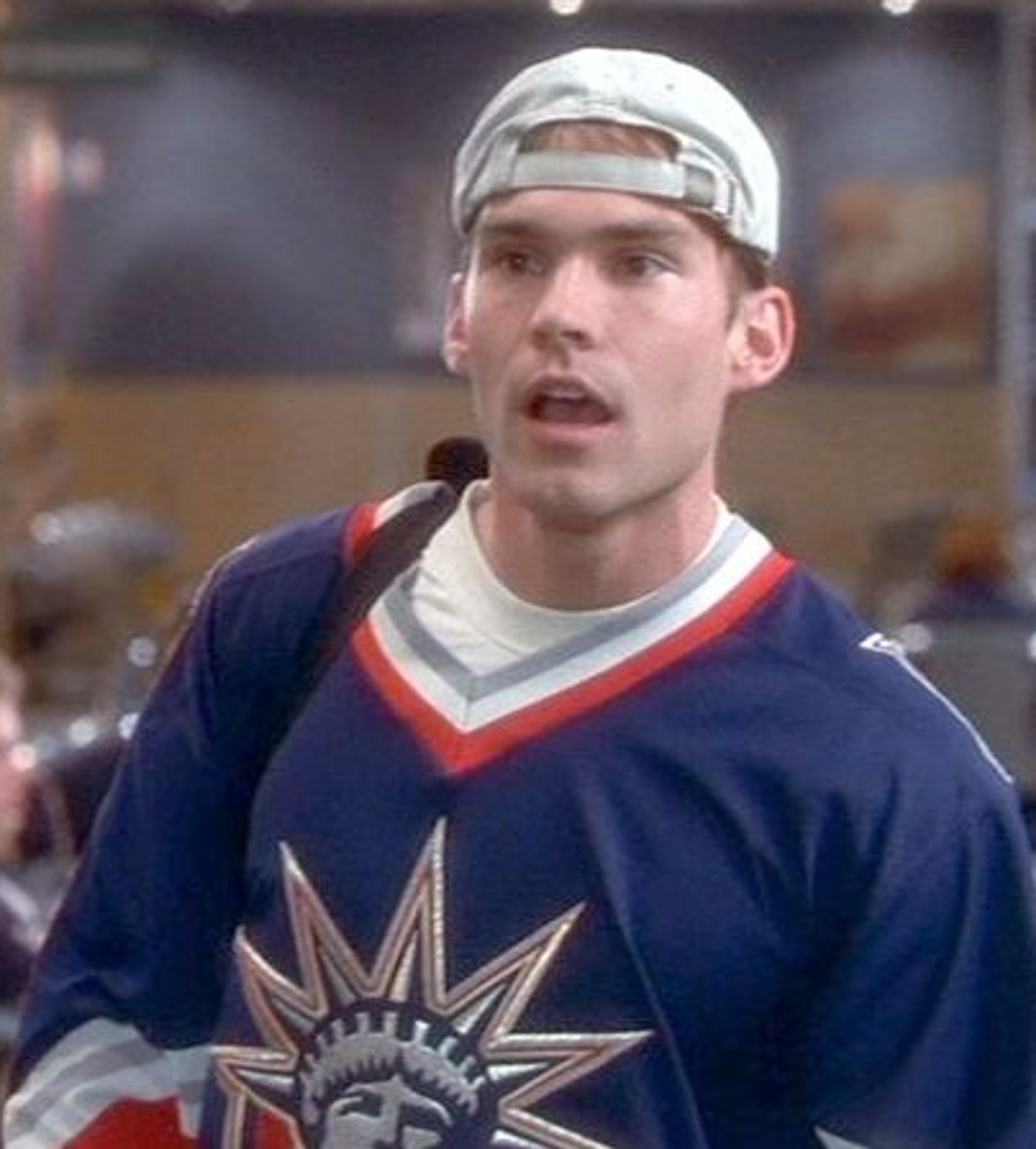 A young man with blonde hair wearing a blue hockey jersey