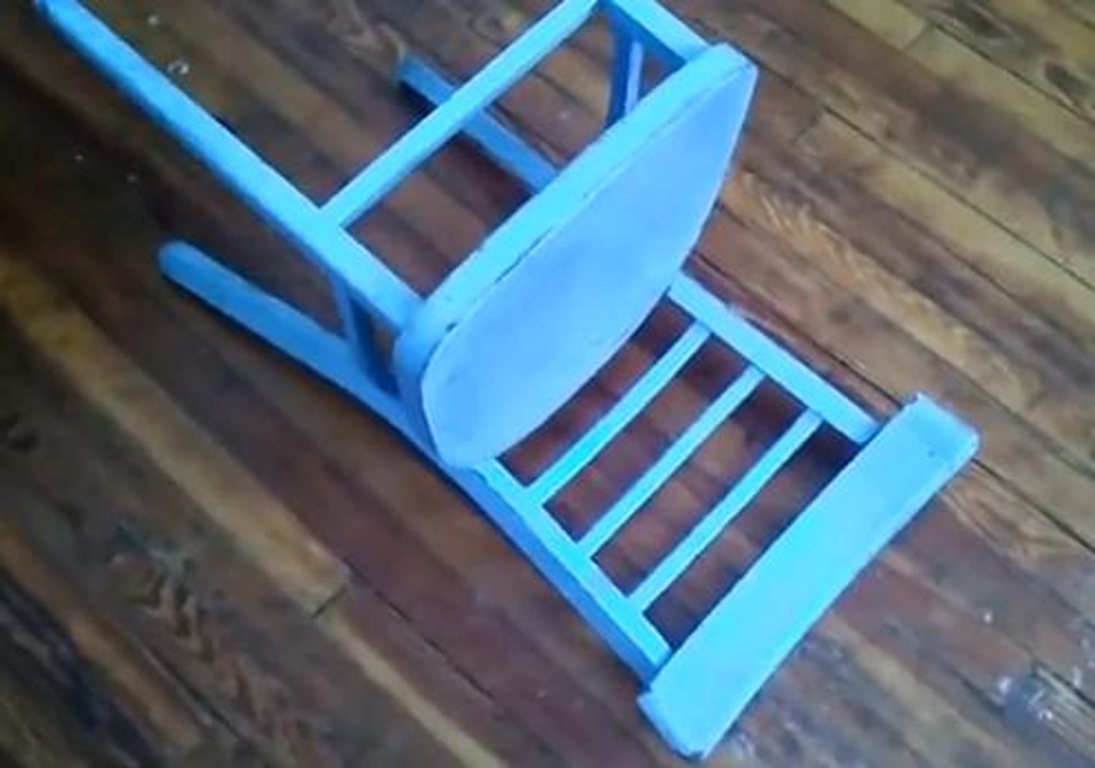A simple, handmade blue wooden chair on a wooden floor