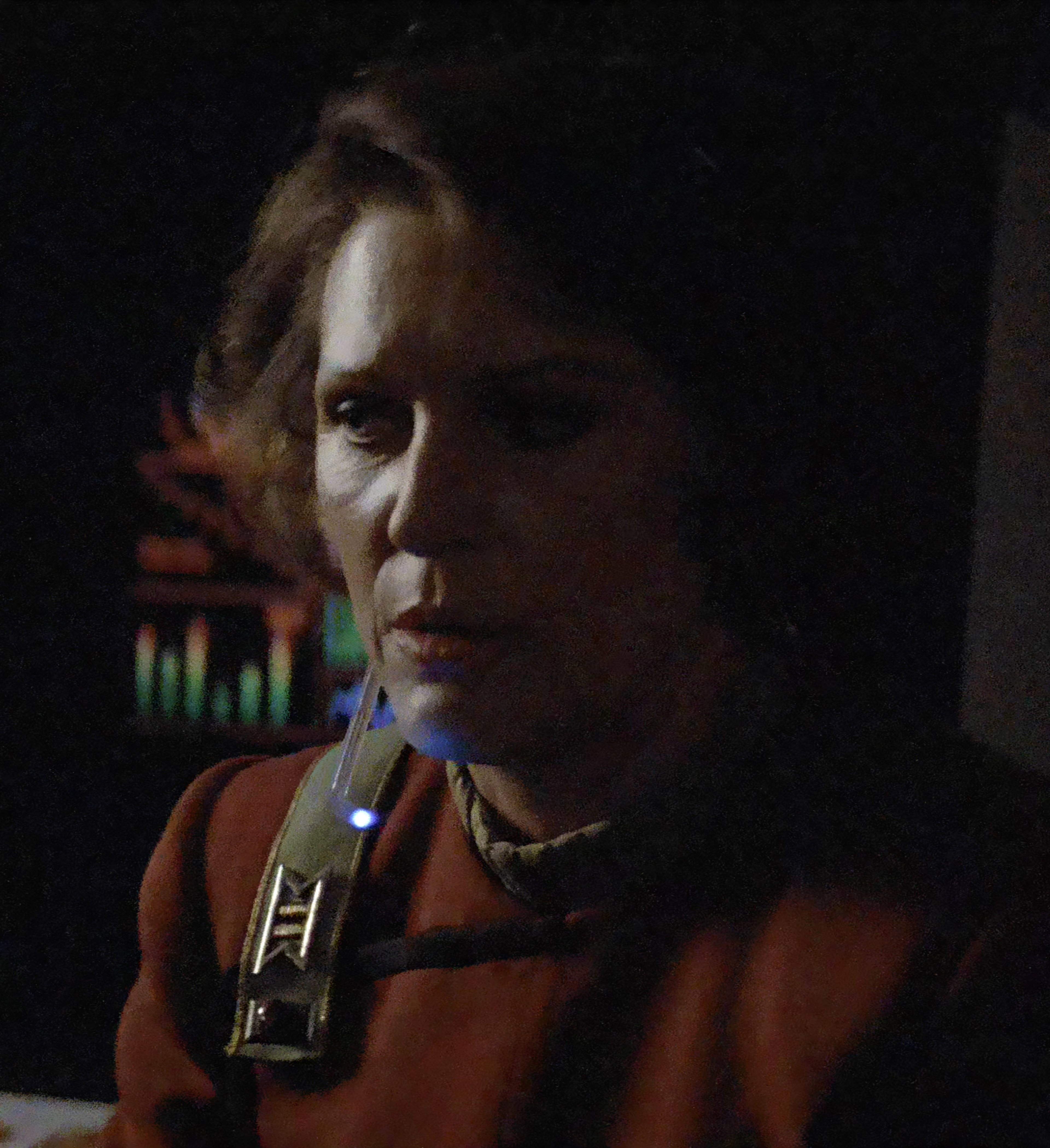 A woman in a red Starfleet medical uniform with a serious expression