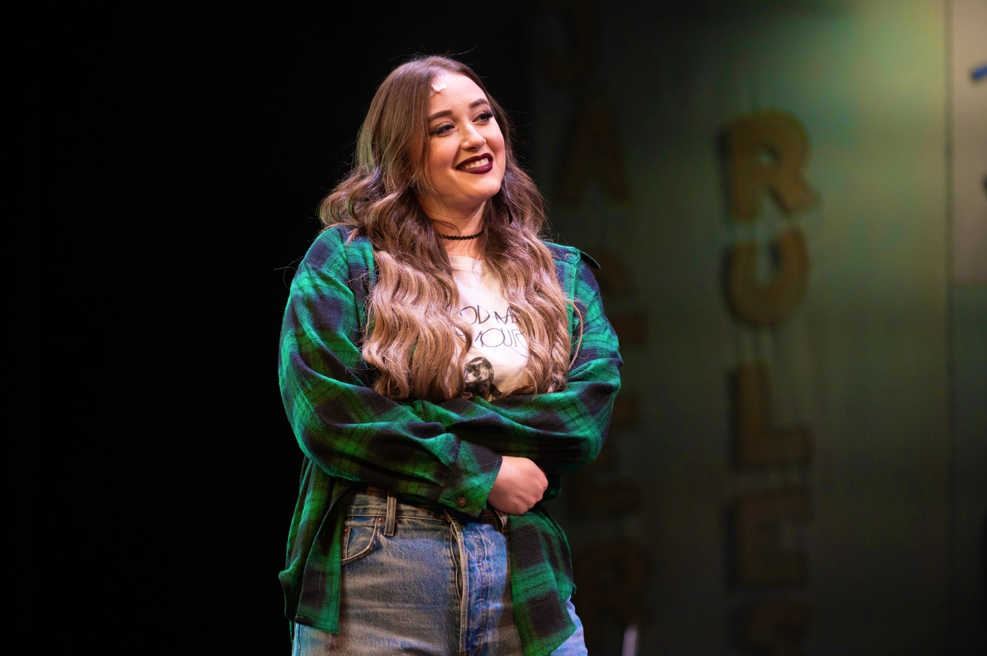 A young woman with long brown hair wearing a green sweater