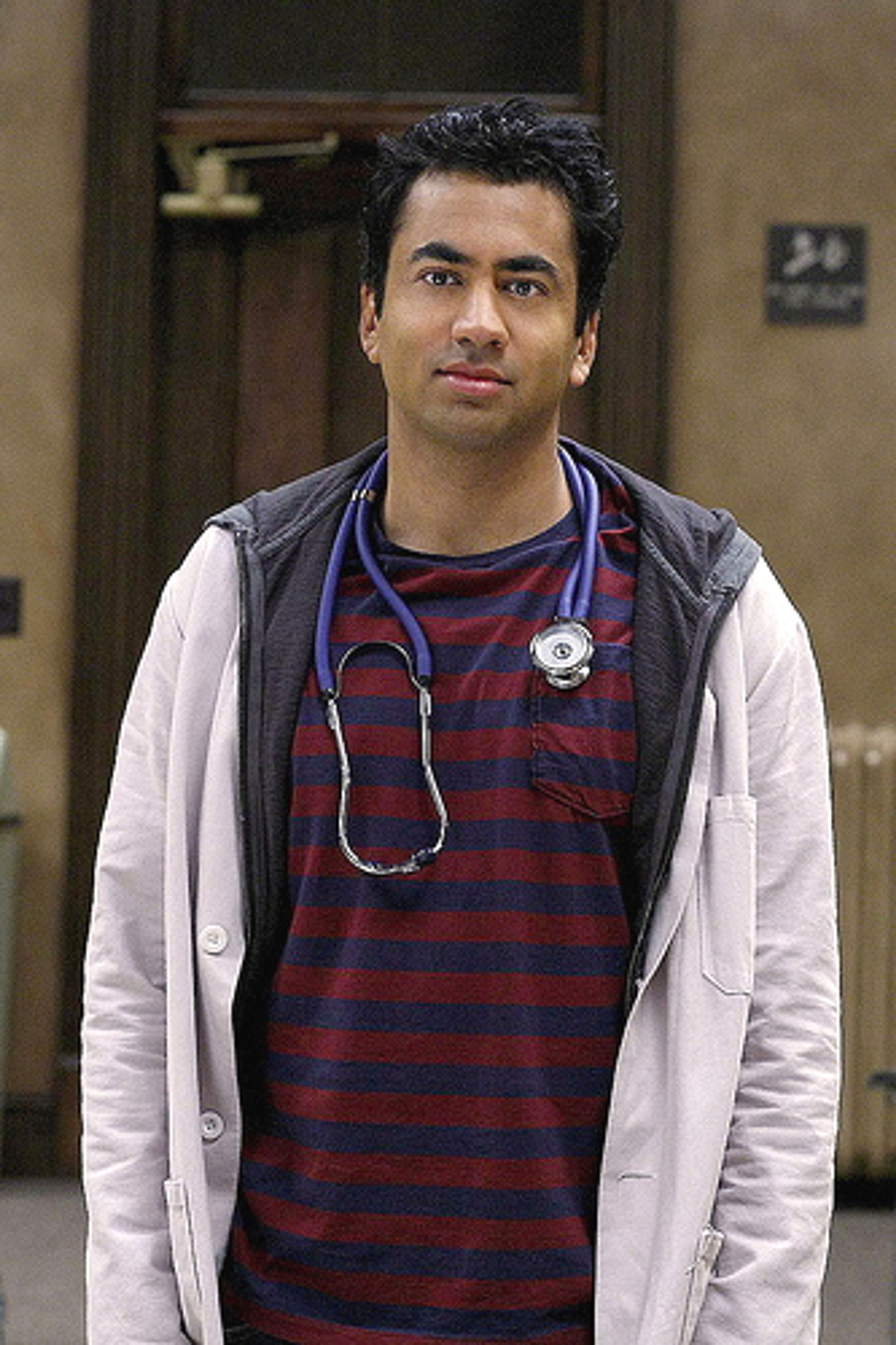 A young Asian man in a medical setting wearing a lab coat and stethoscope