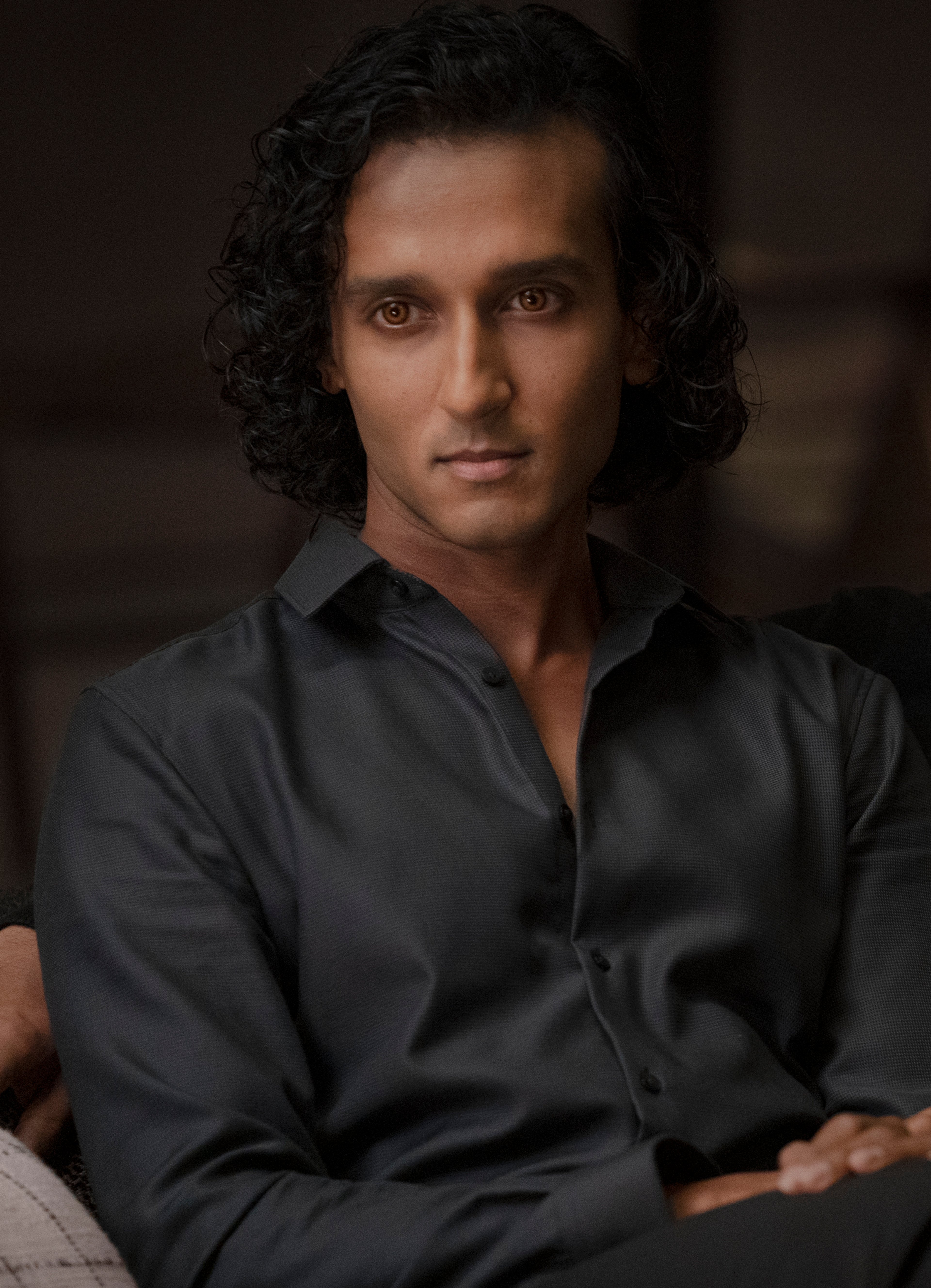A man with dark curly hair and pale skin wearing a black shirt