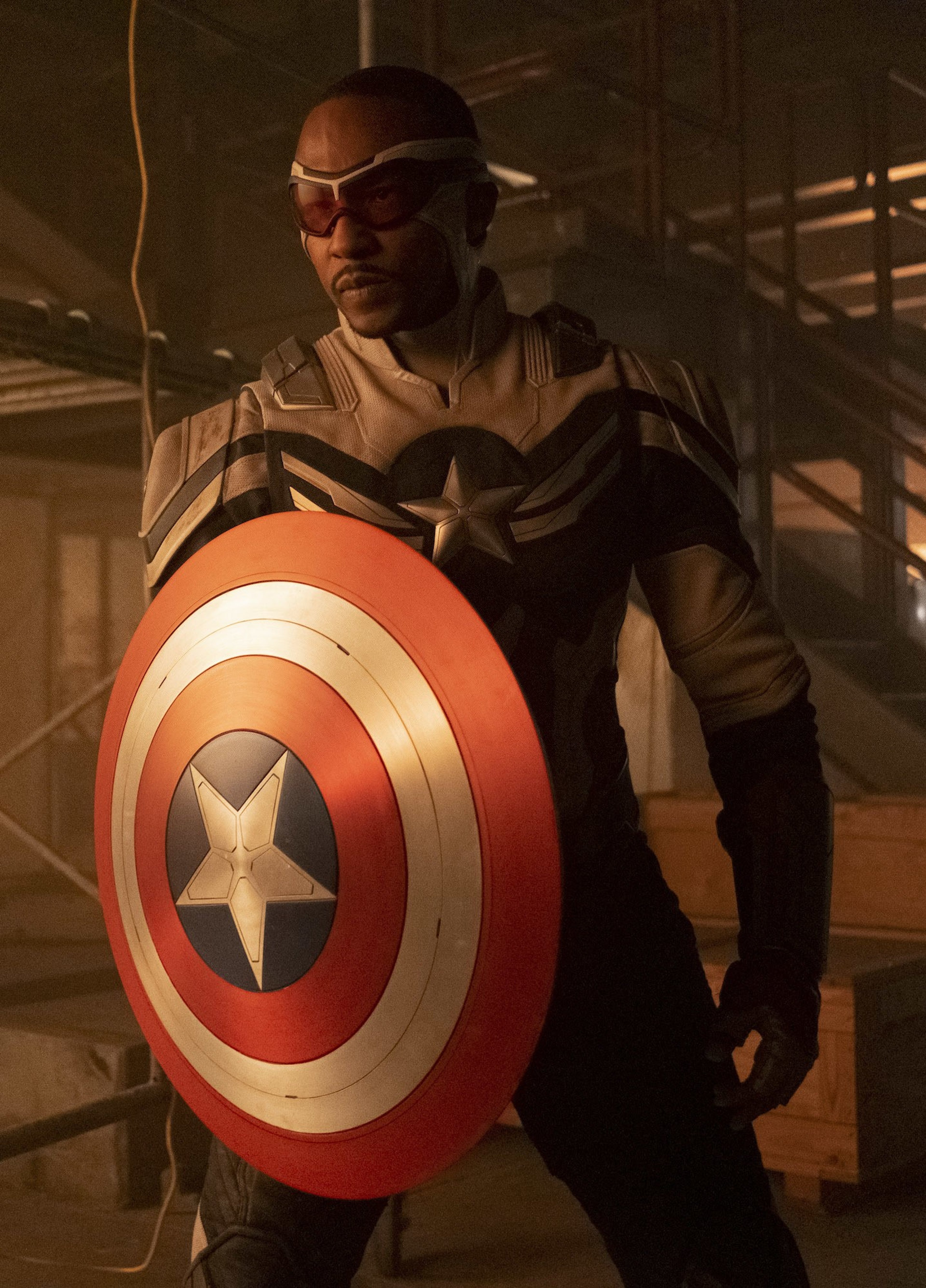 A man in a black tactical outfit holding a circular shield with a star symbol