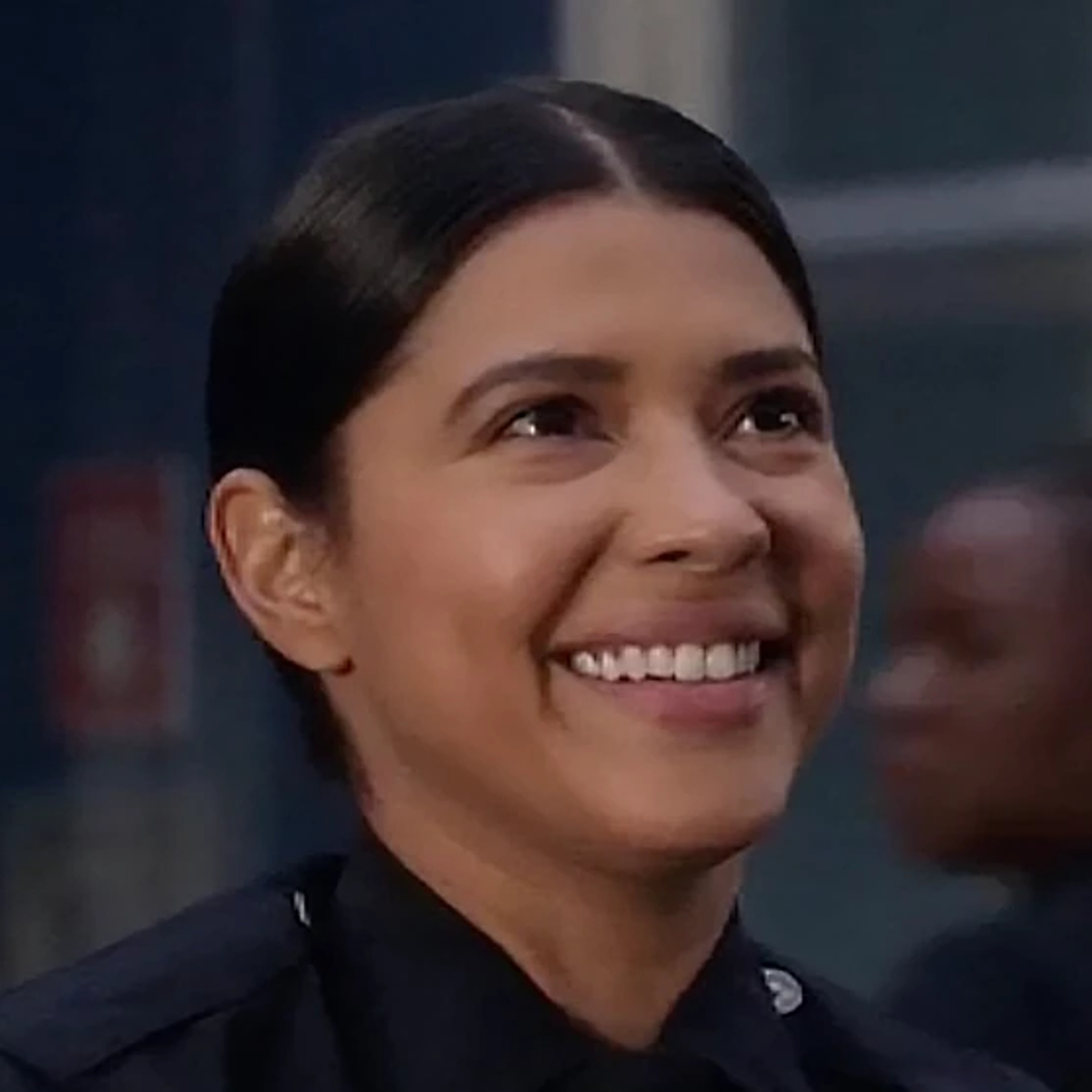 A young female police officer in uniform, smiling at the camera.