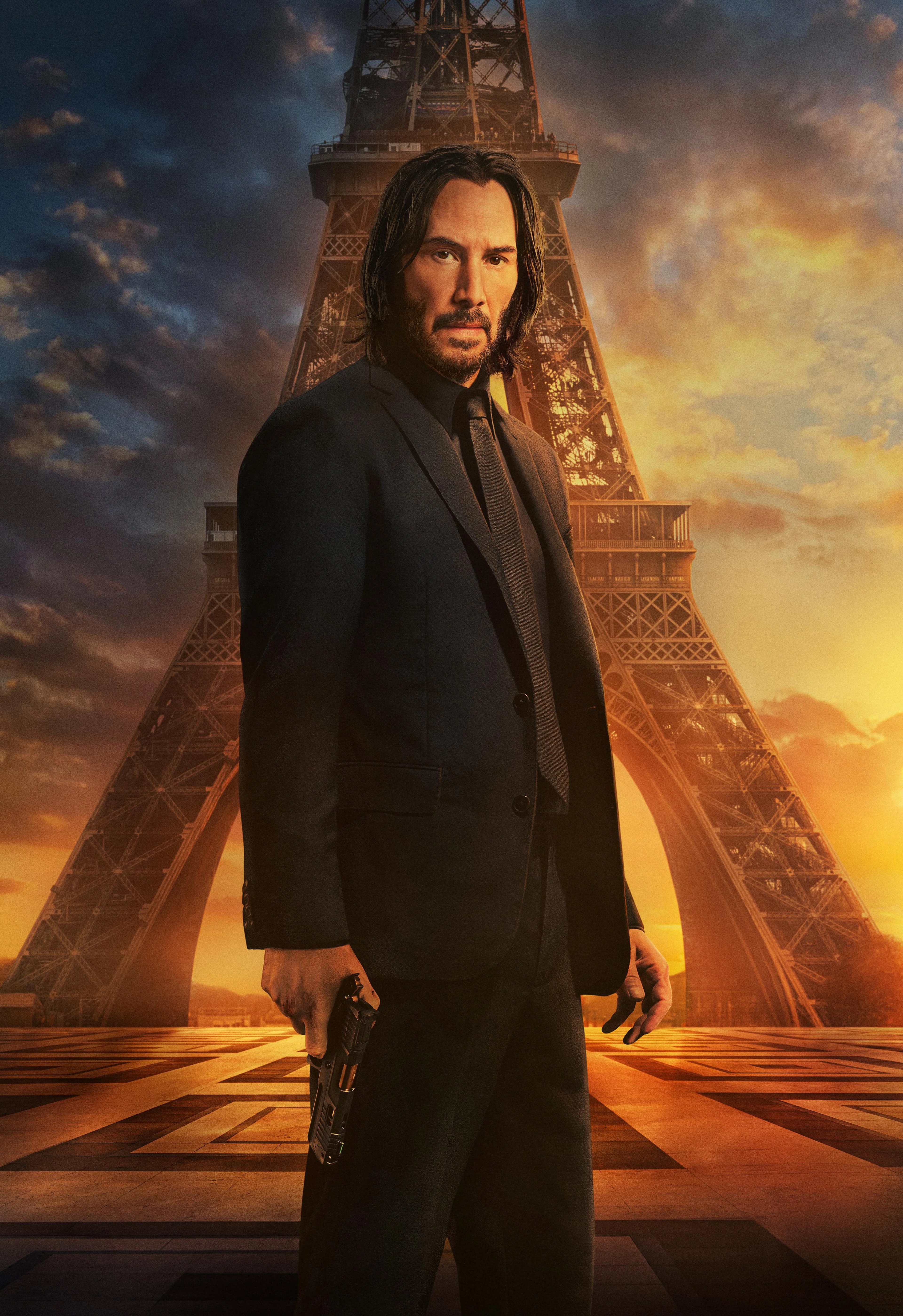 A man in a black suit standing in front of the Eiffel Tower