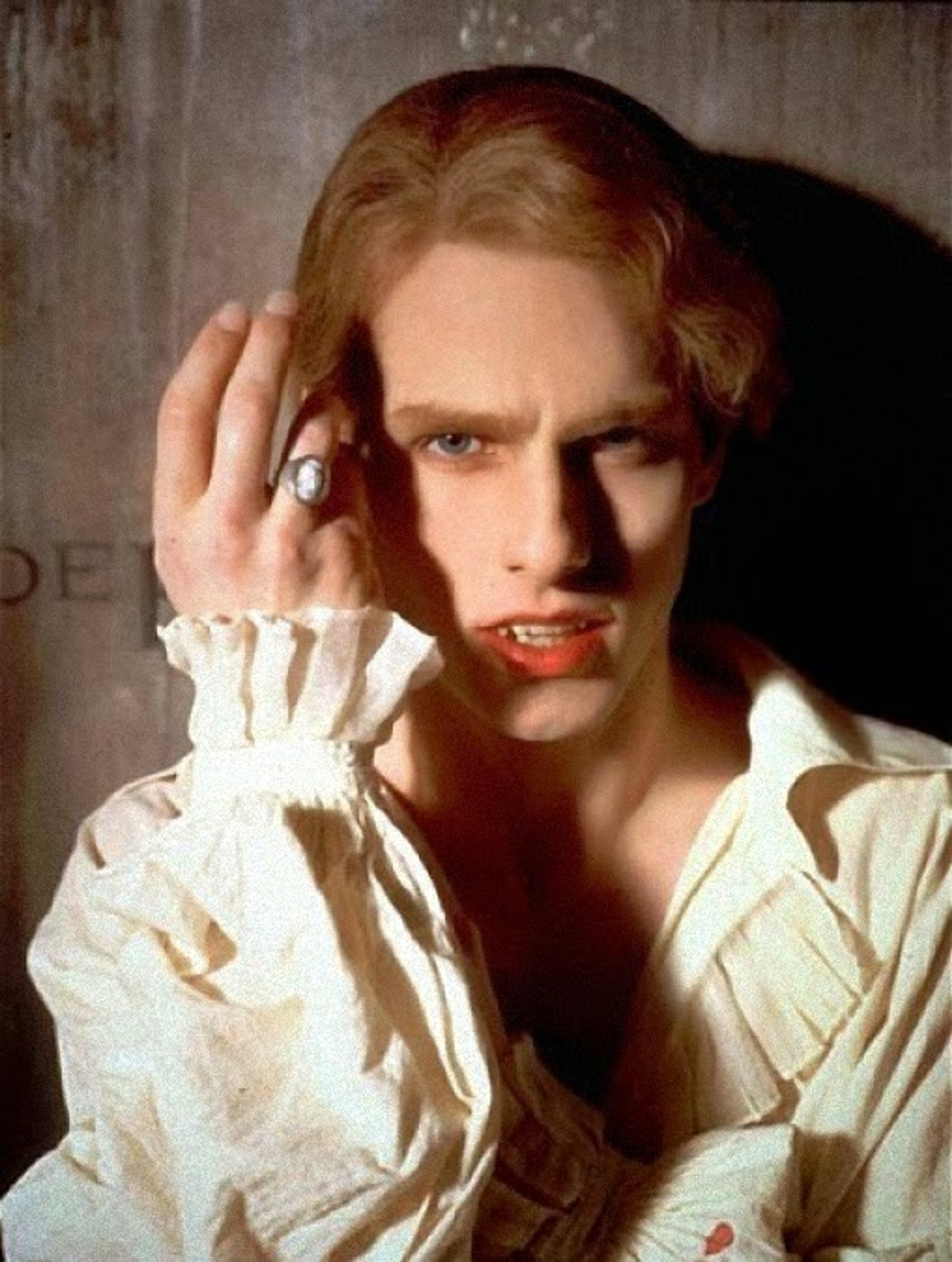 A close-up portrait of a pale, red-haired man with an intense, piercing gaze