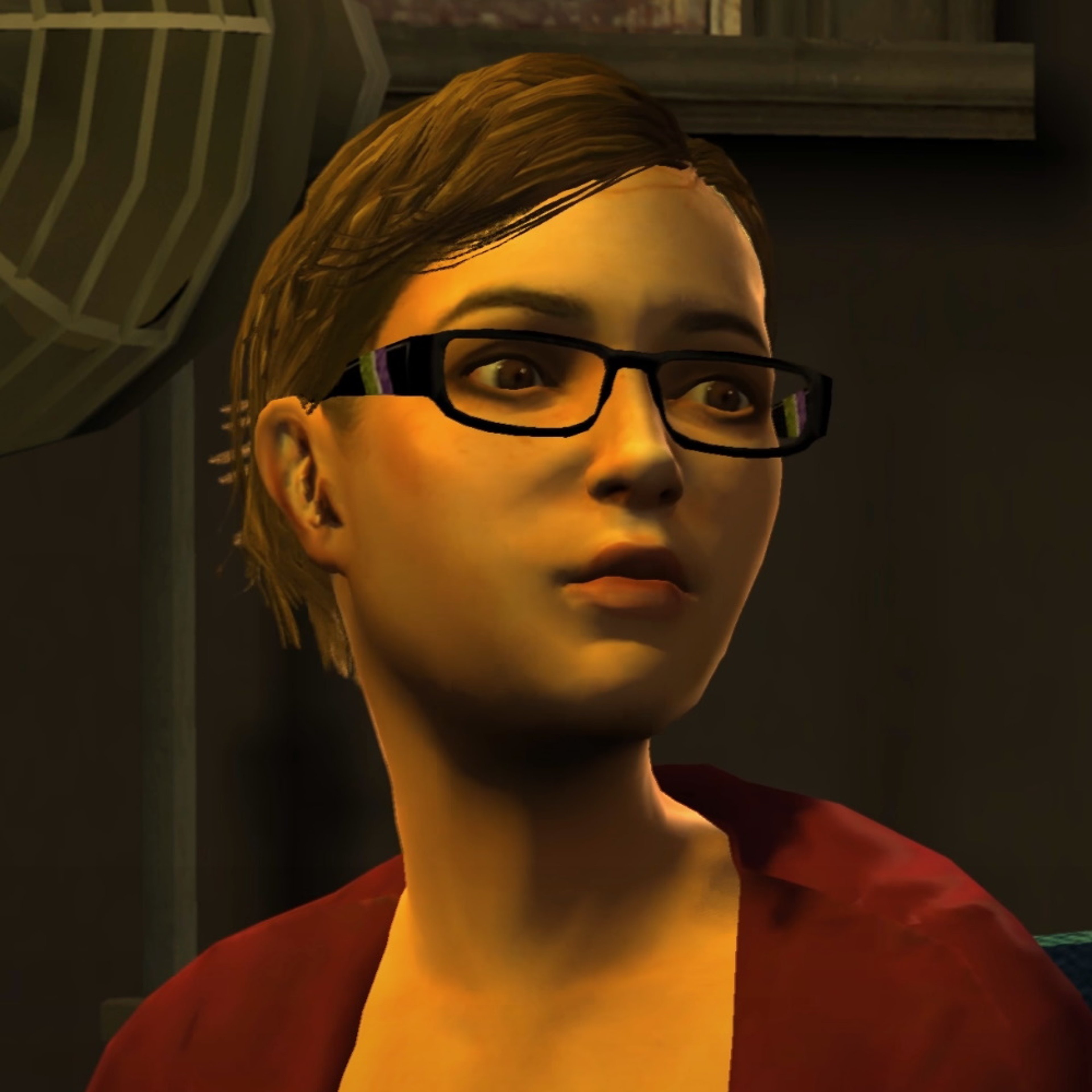 A young woman with glasses and a red shirt in a dimly lit setting