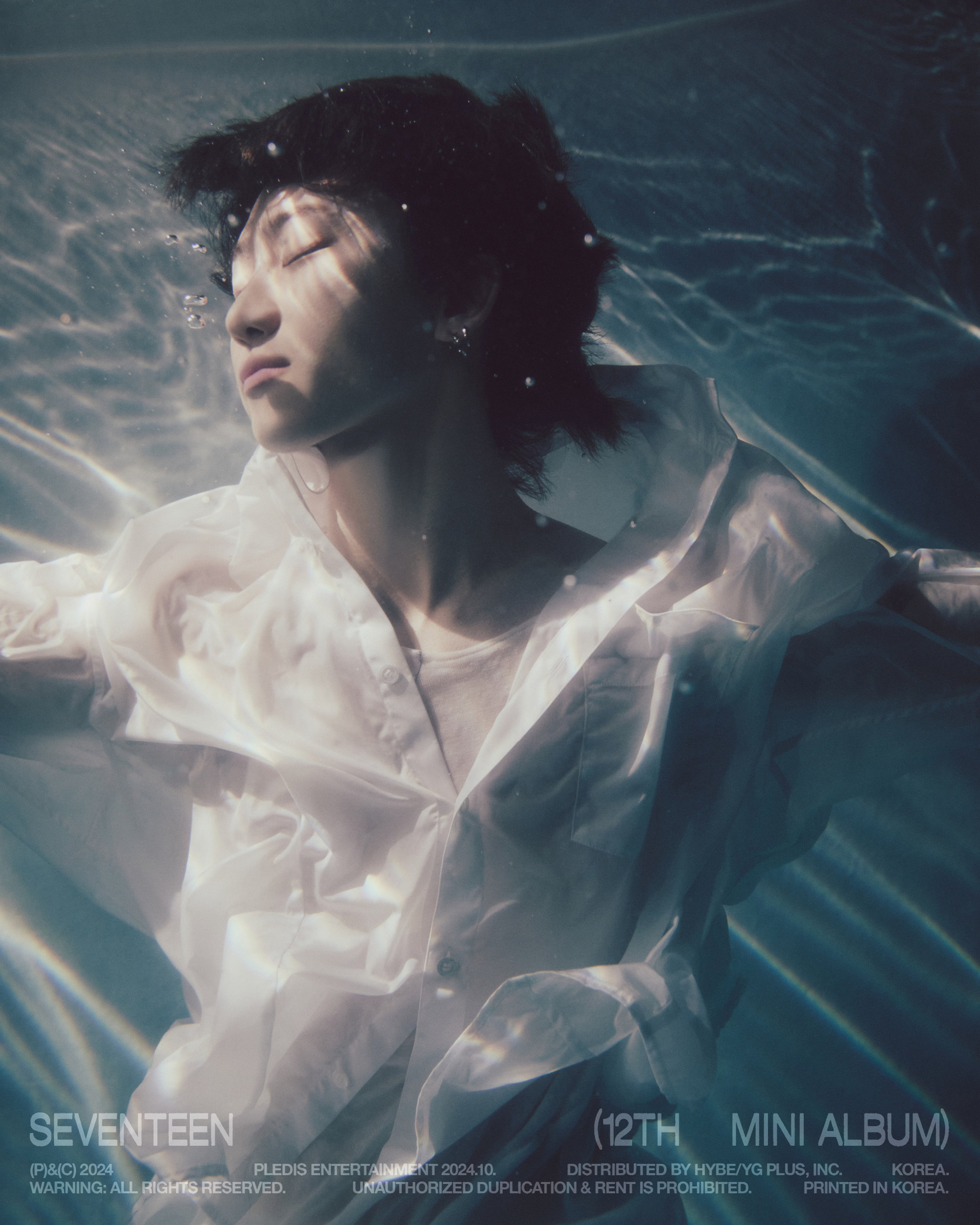 A young Asian man floating in water, wearing a white flowing garment