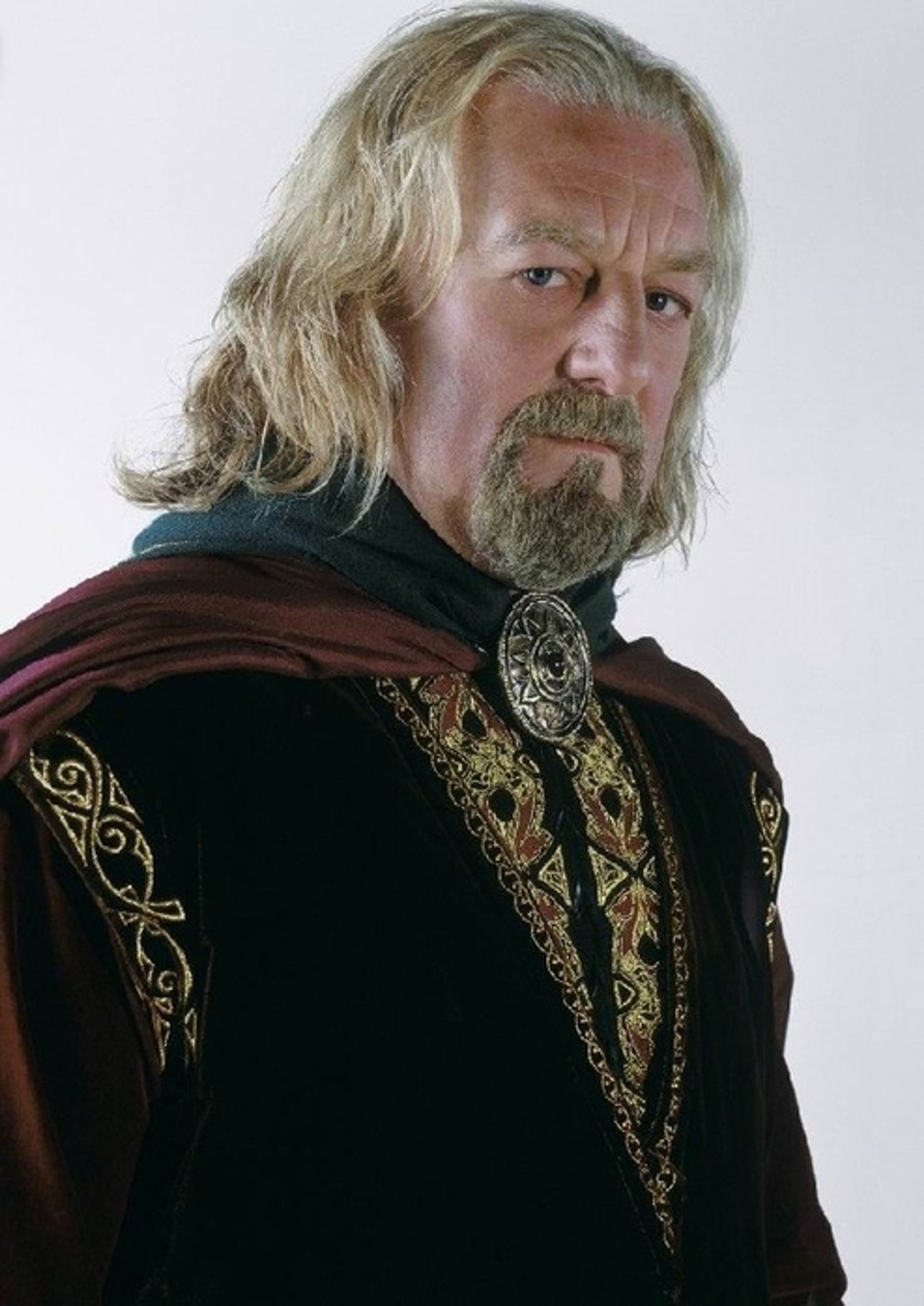 An elderly man with long gray hair and a beard, wearing ornate robes and a cloak.