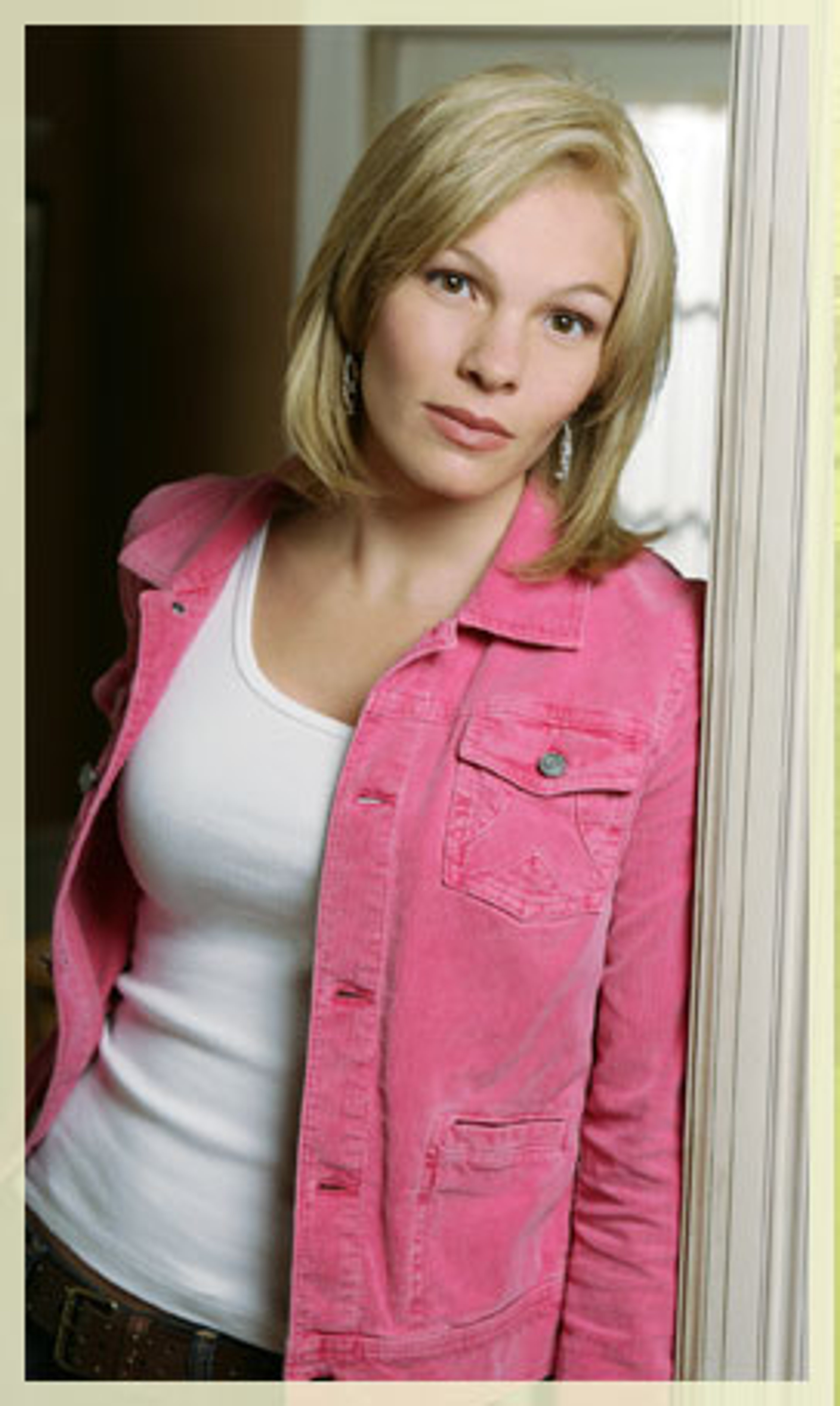 A portrait of a young blonde woman wearing a pink denim jacket