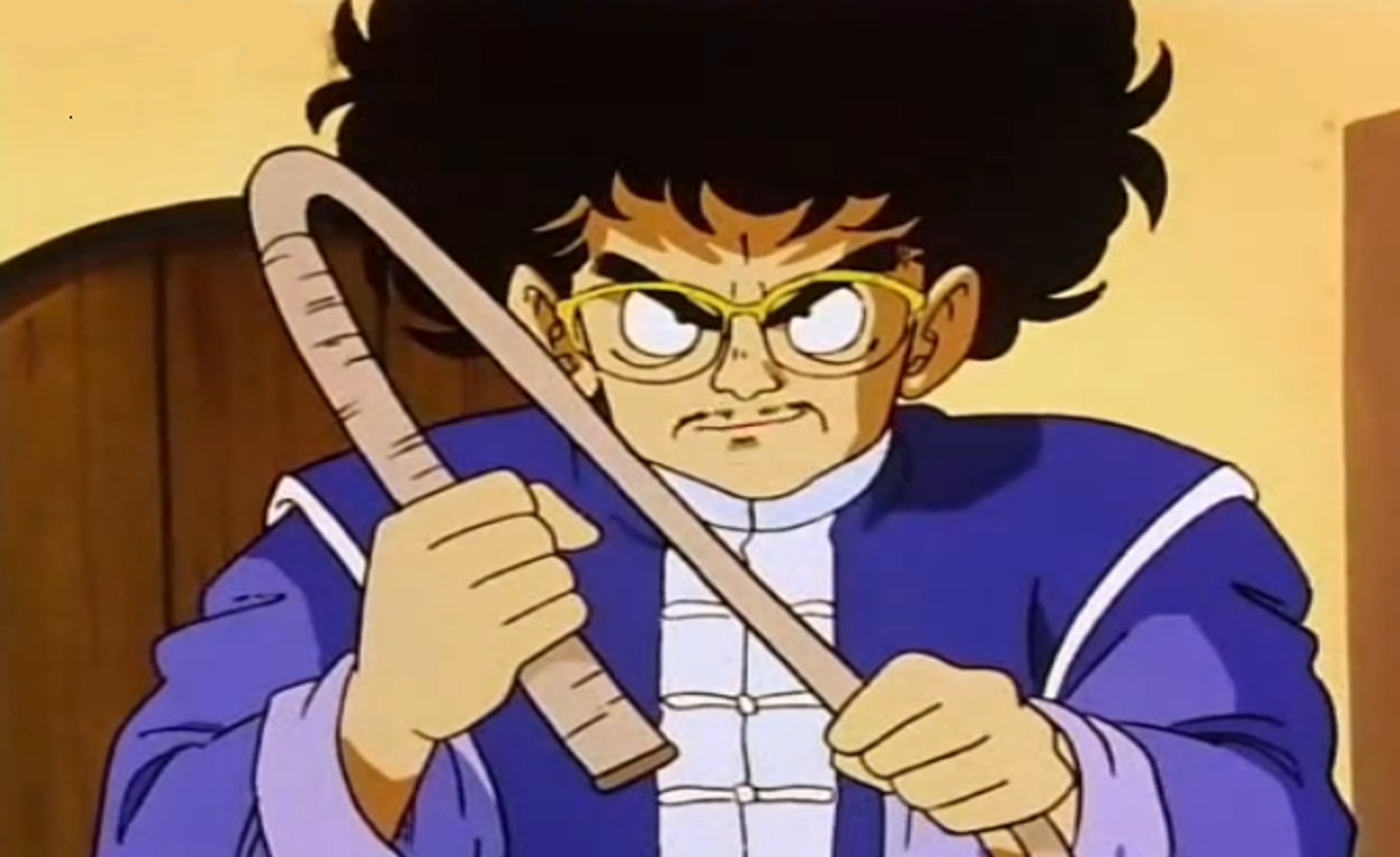 An animated character with an afro hairstyle, wearing traditional Chinese Kung Fu garb, holding a wooden staff or weapon and displaying an angry expression.