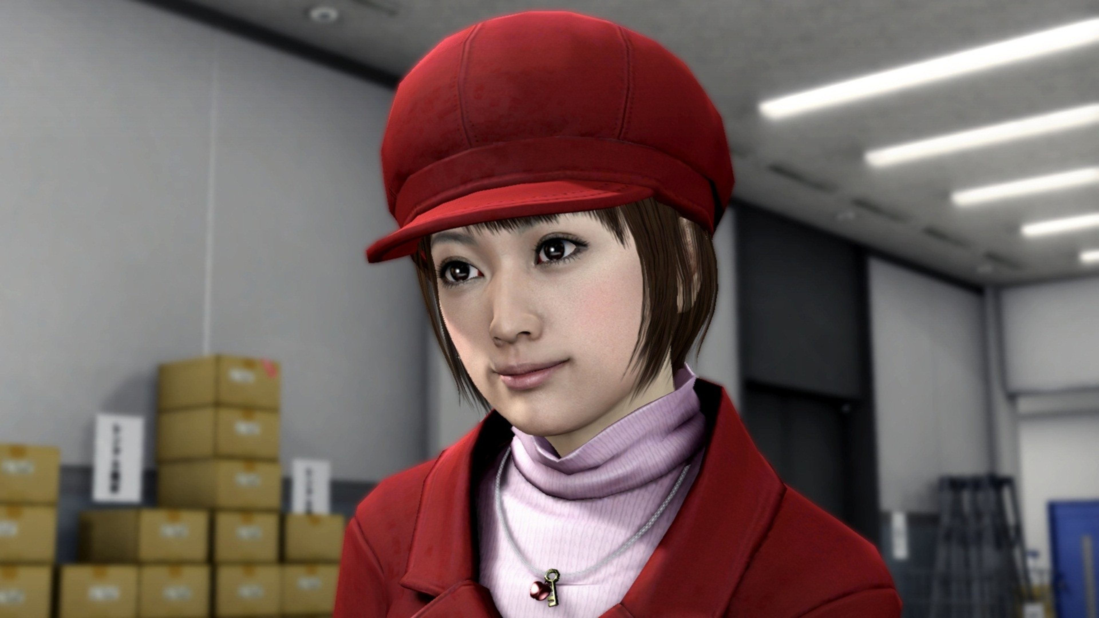 A young woman with short dark hair wearing a red hat and pink scarf, standing in a professional setting.
