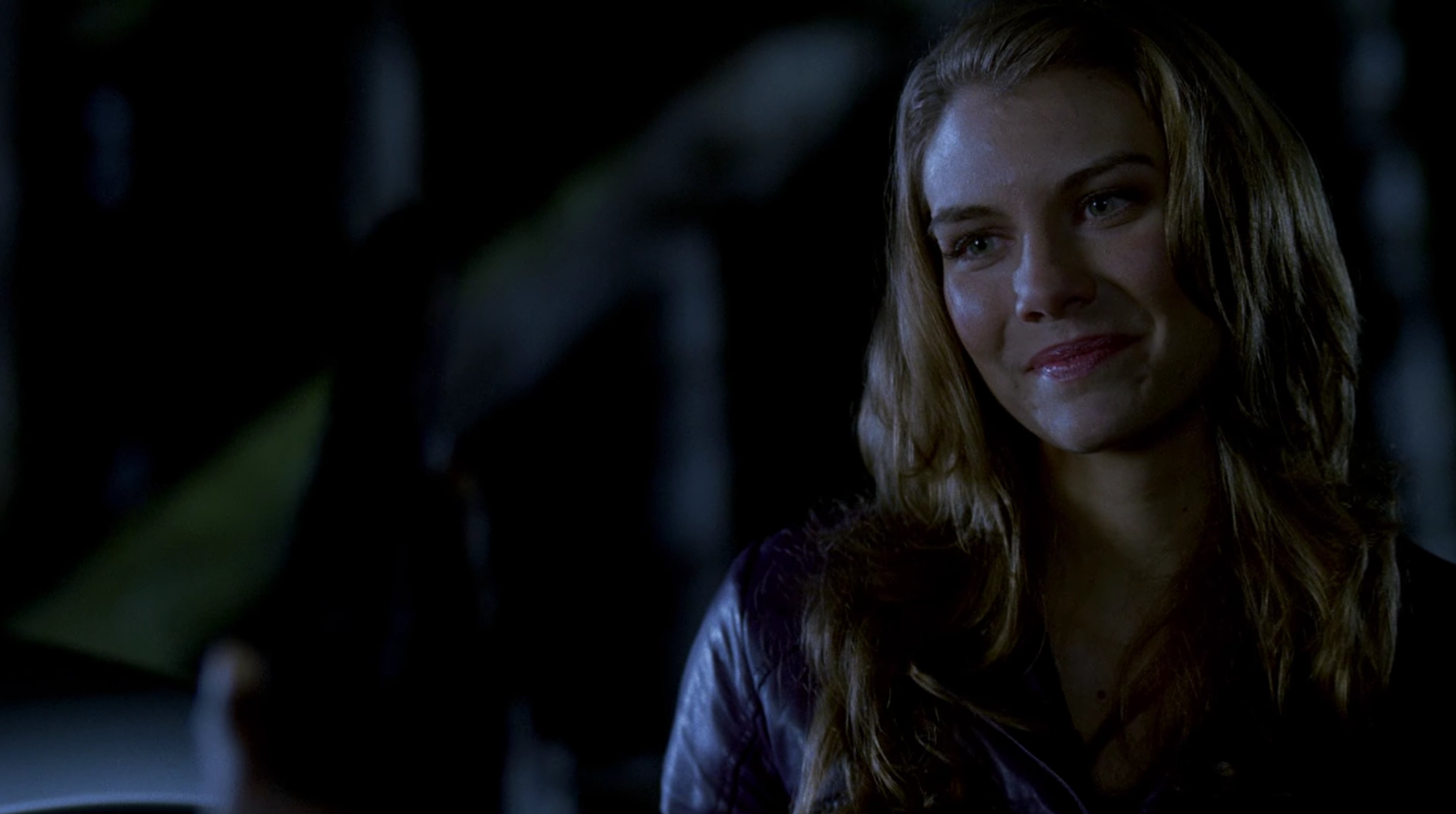 A young woman with dark hair and a serious expression, wearing a dark shirt or jacket.