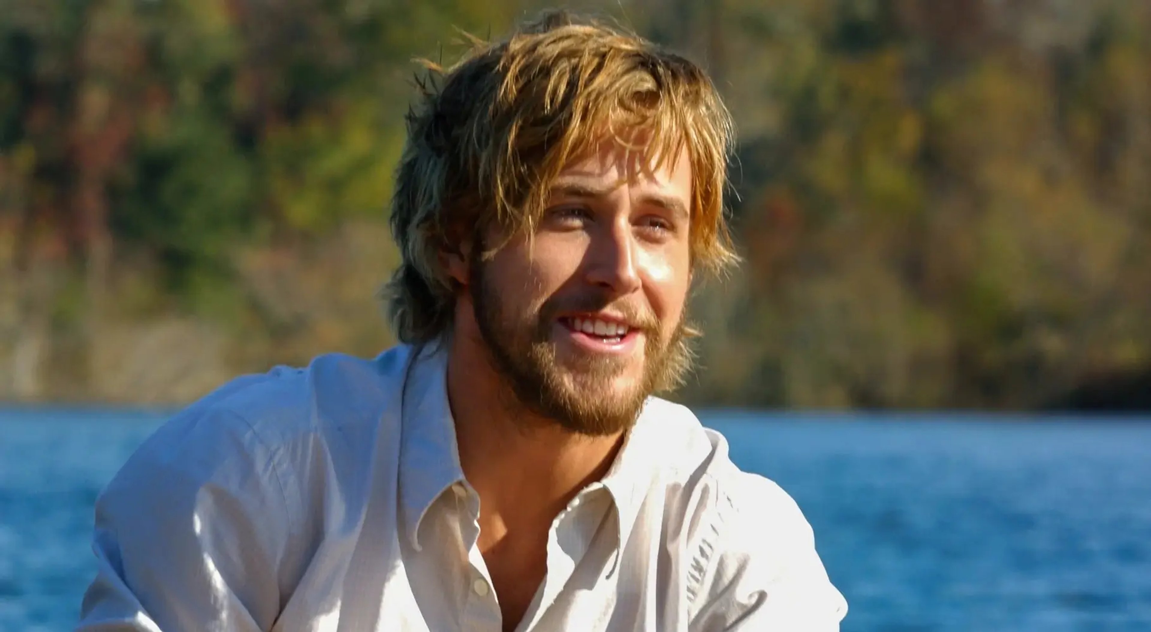 A man with brown hair and a beard, wearing a white shirt, in an outdoor setting
