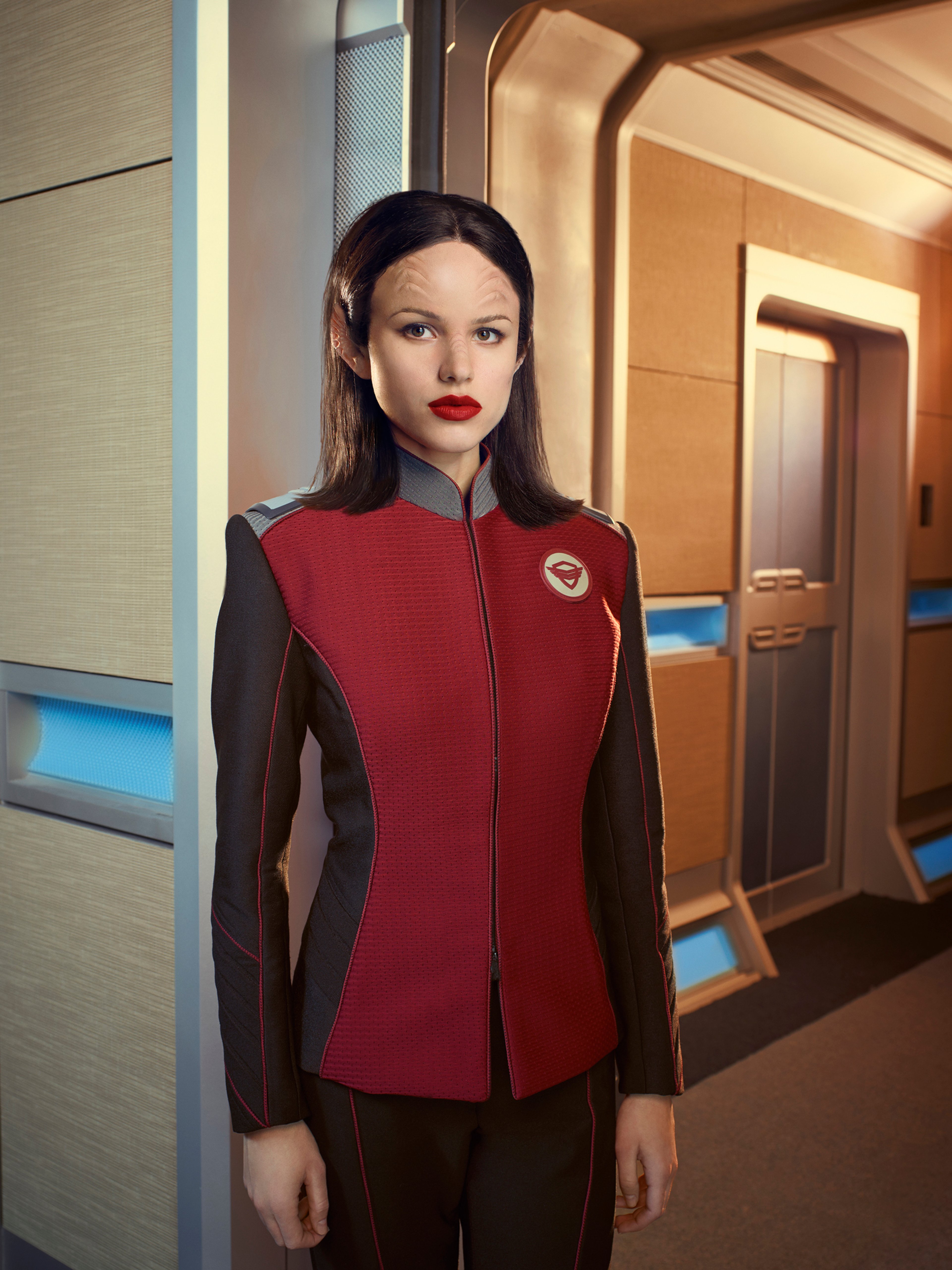A young woman in a red and brown uniform standing in a hallway
