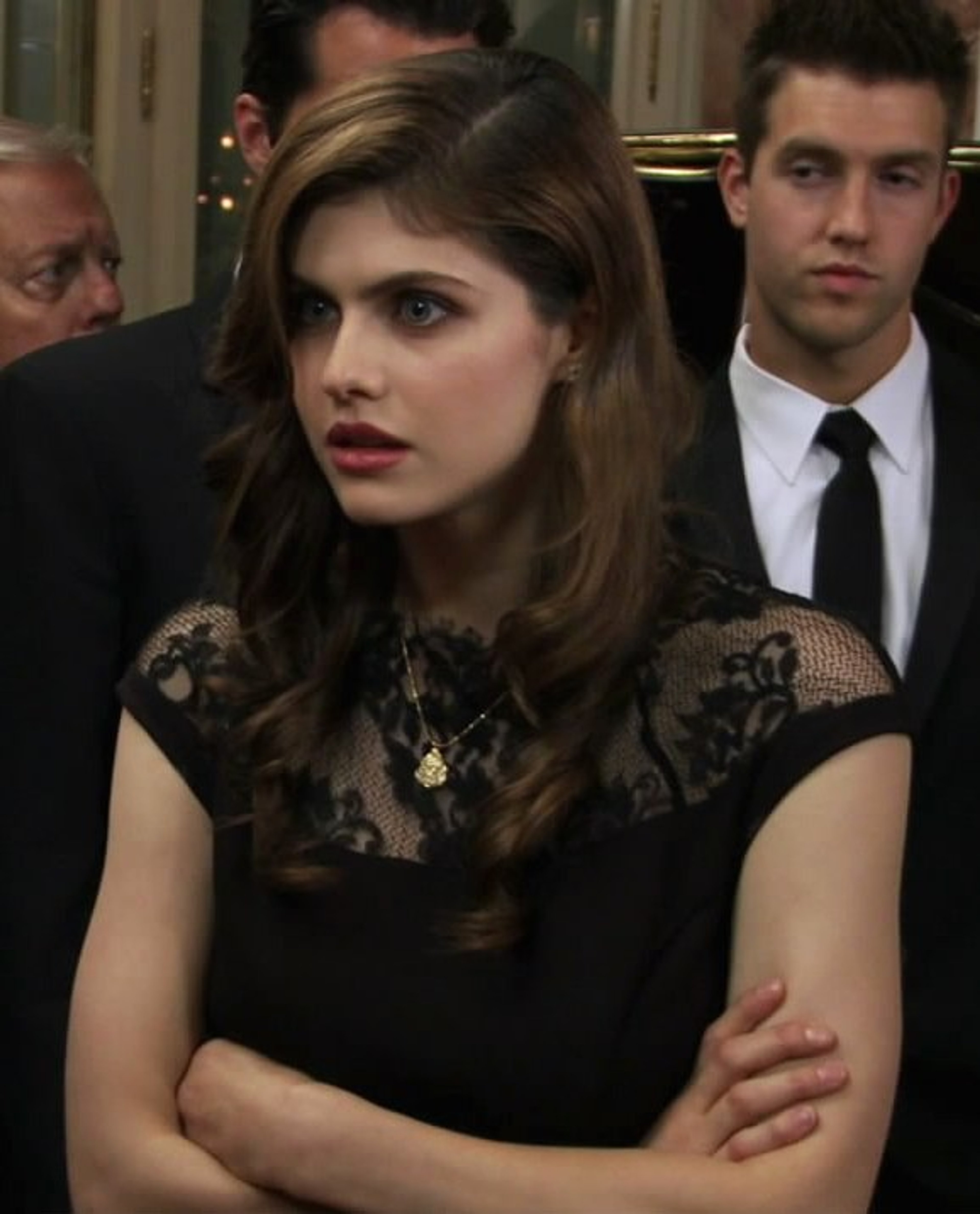 A young woman in a black lace dress with a serious expression