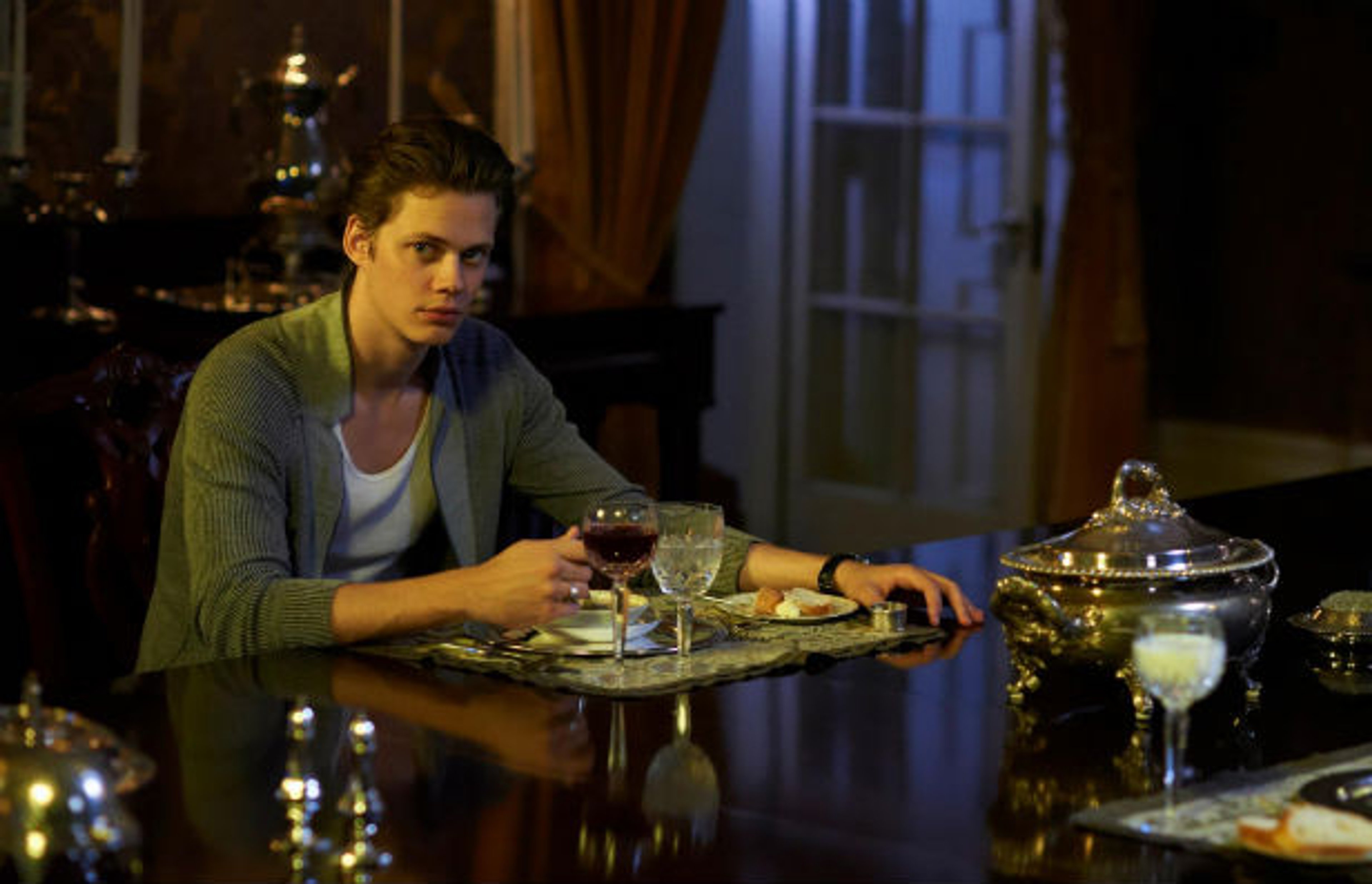 A young man sitting at a table in a dimly lit room