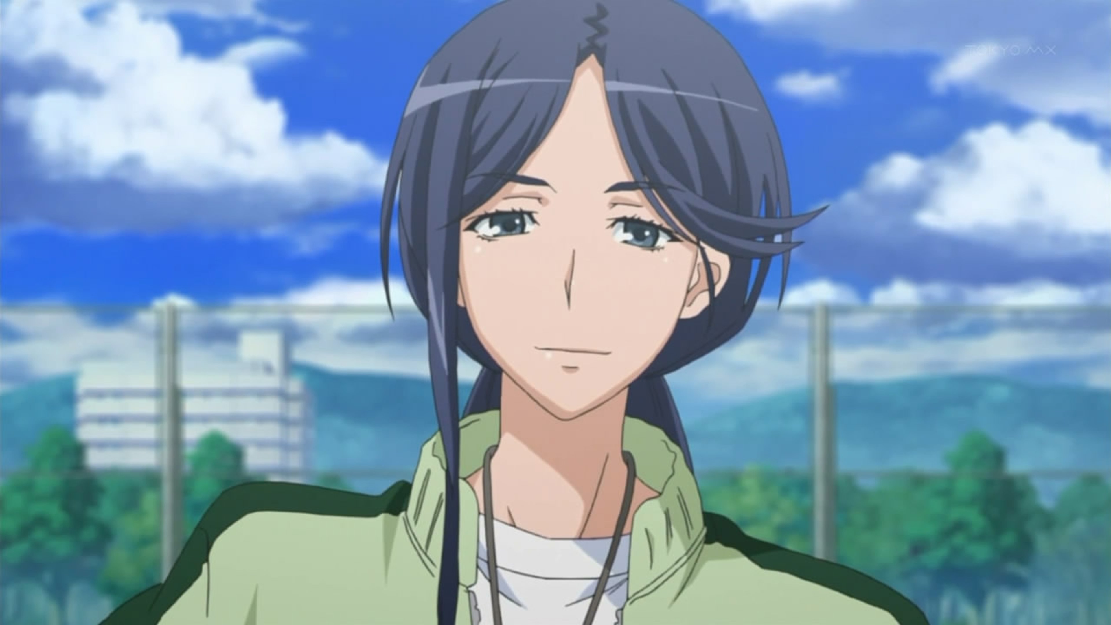 A serious-looking adult woman with short dark hair wearing a green jacket and pants