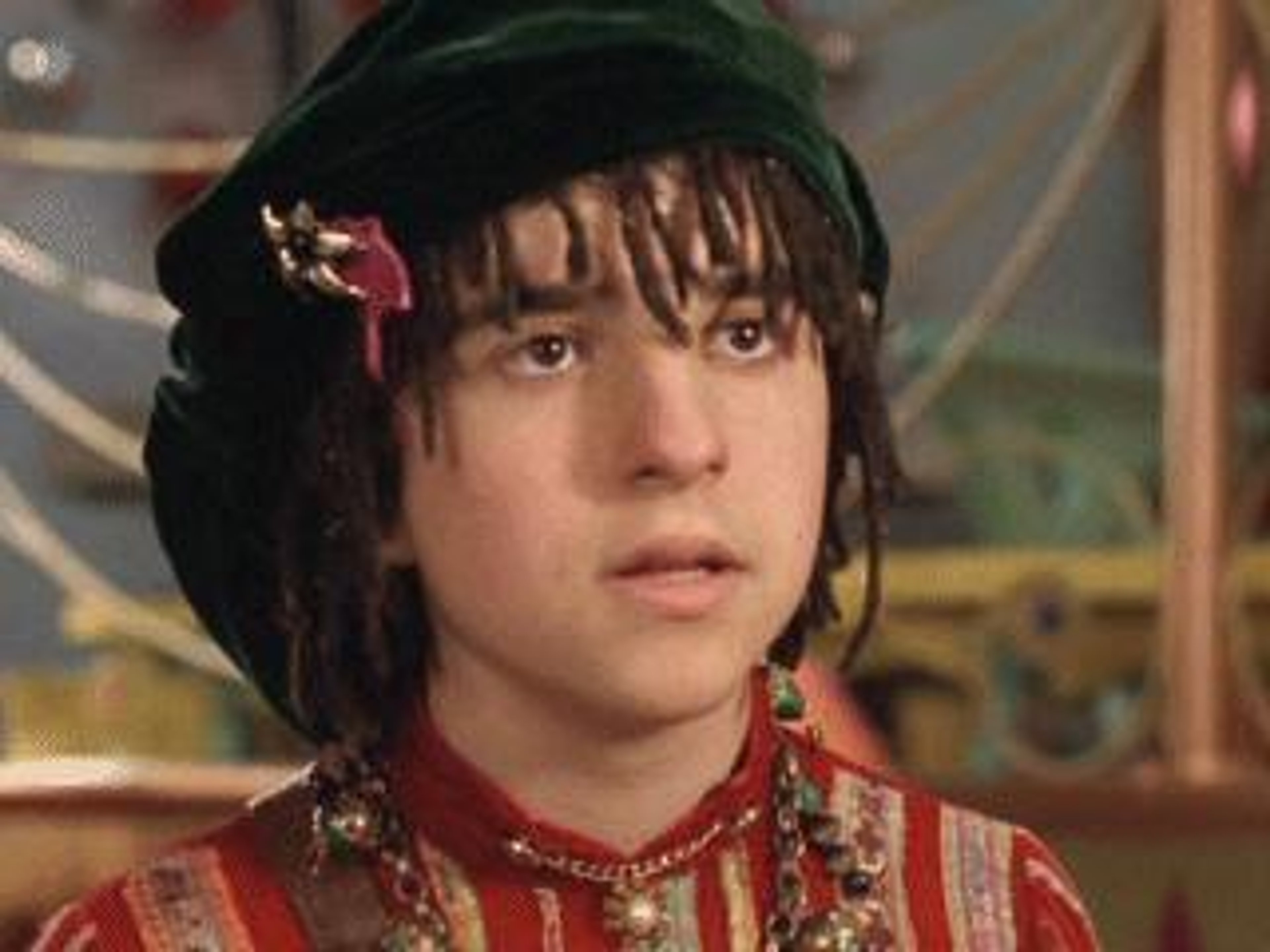 A young male elf-like character with dark hair wearing a red outfit and hat