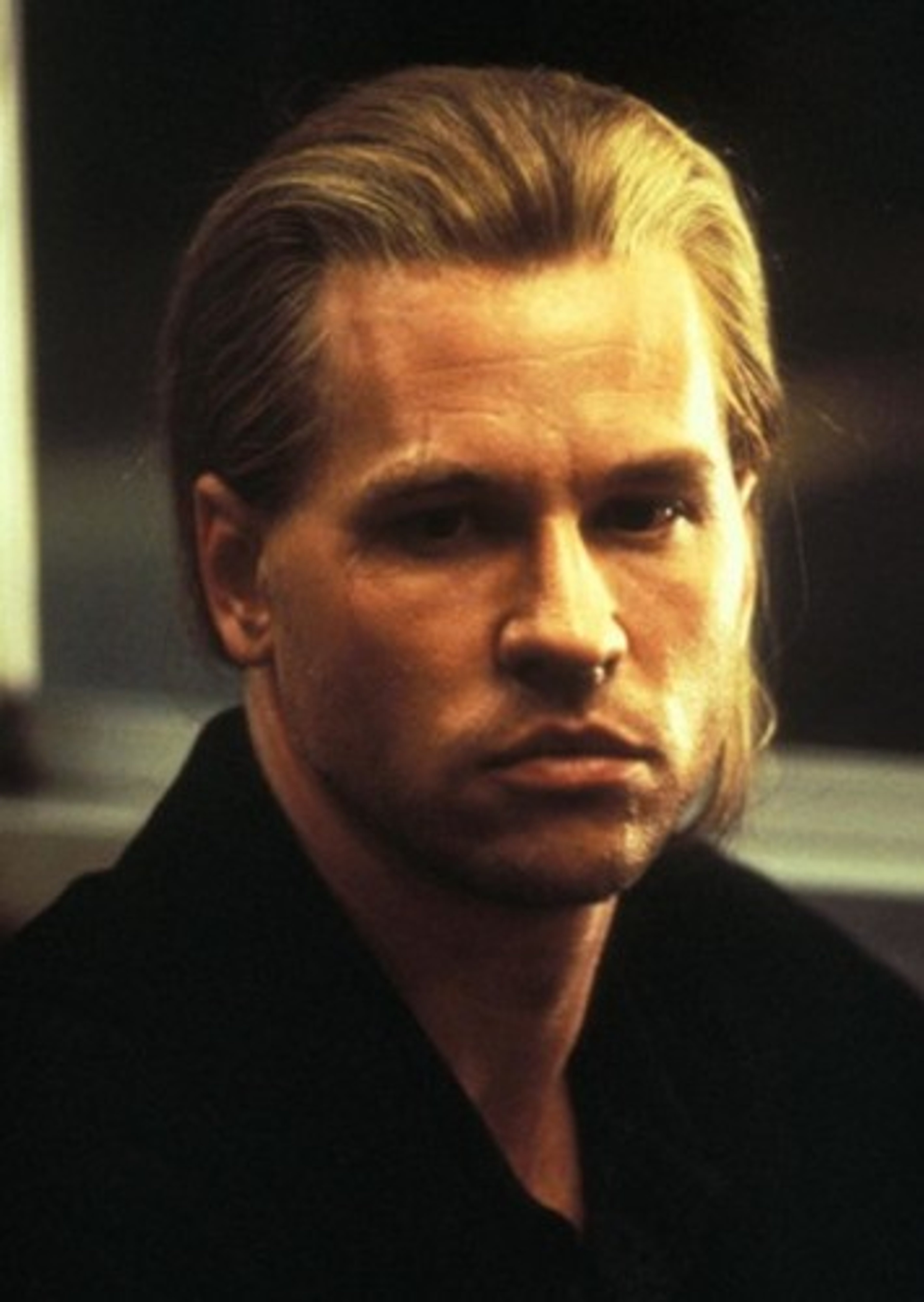 A close-up portrait of a serious-looking man with short blonde hair