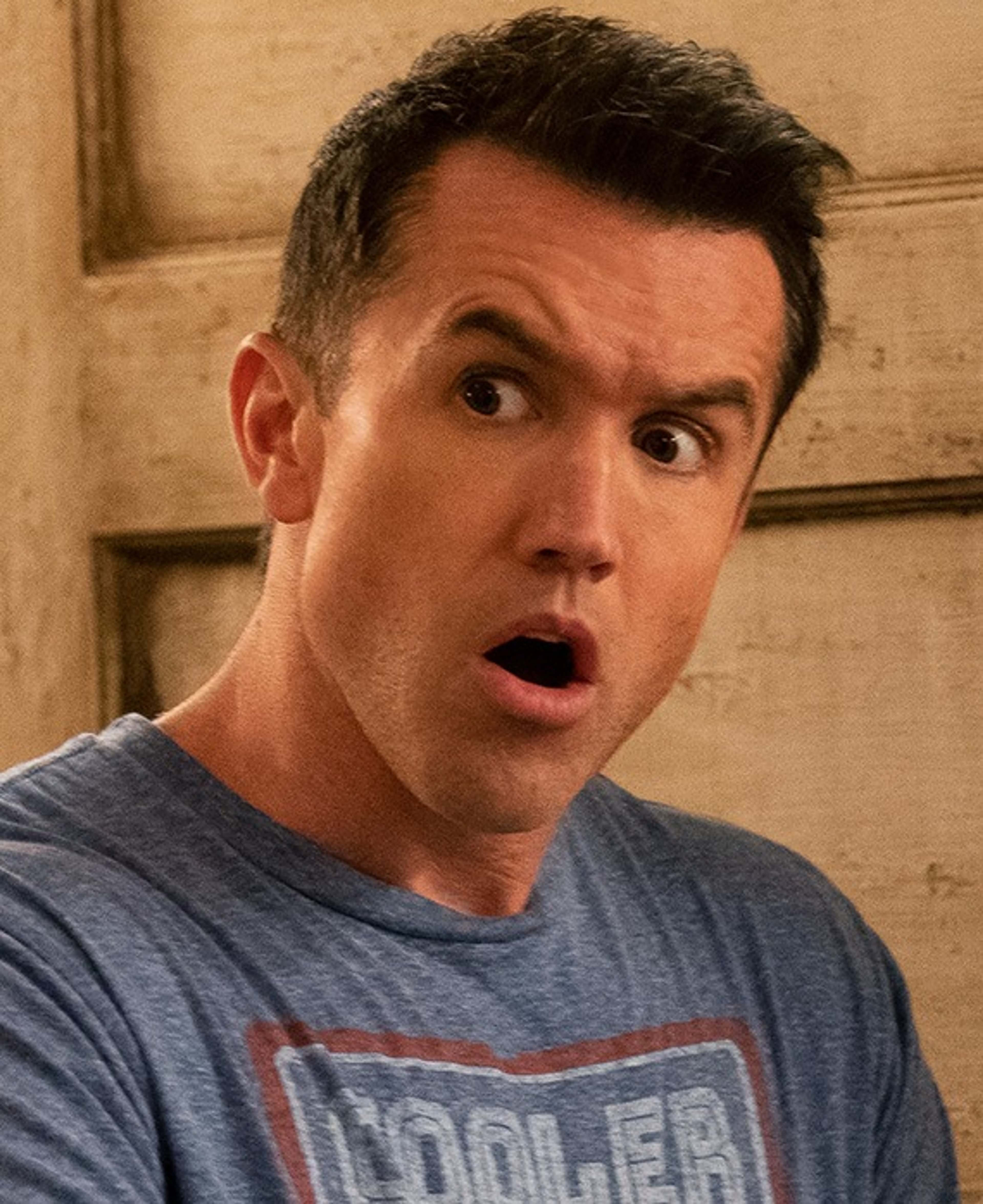 A middle-aged man with a gruff appearance wearing a gray t-shirt