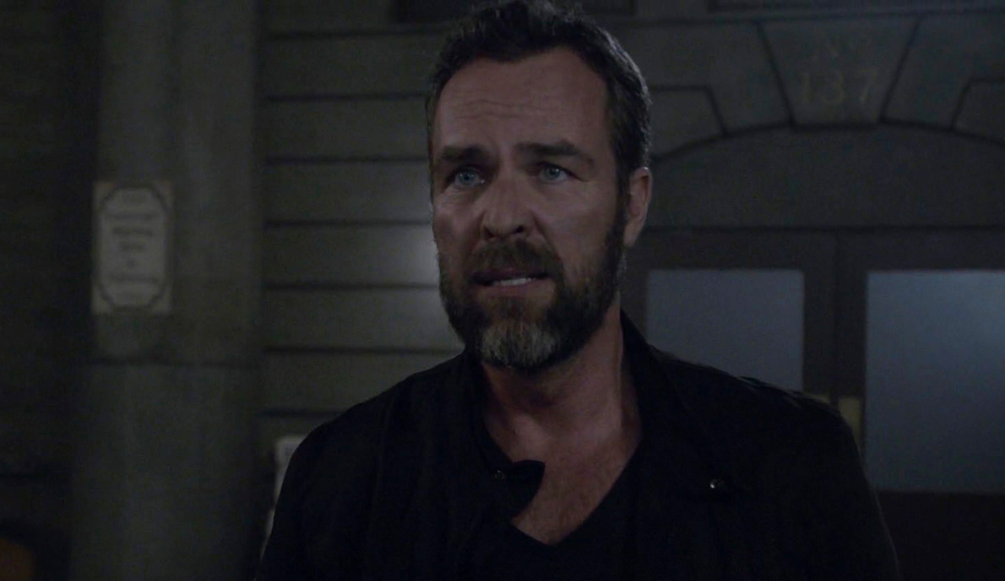 A middle-aged man with a beard and serious expression, wearing a black jacket.