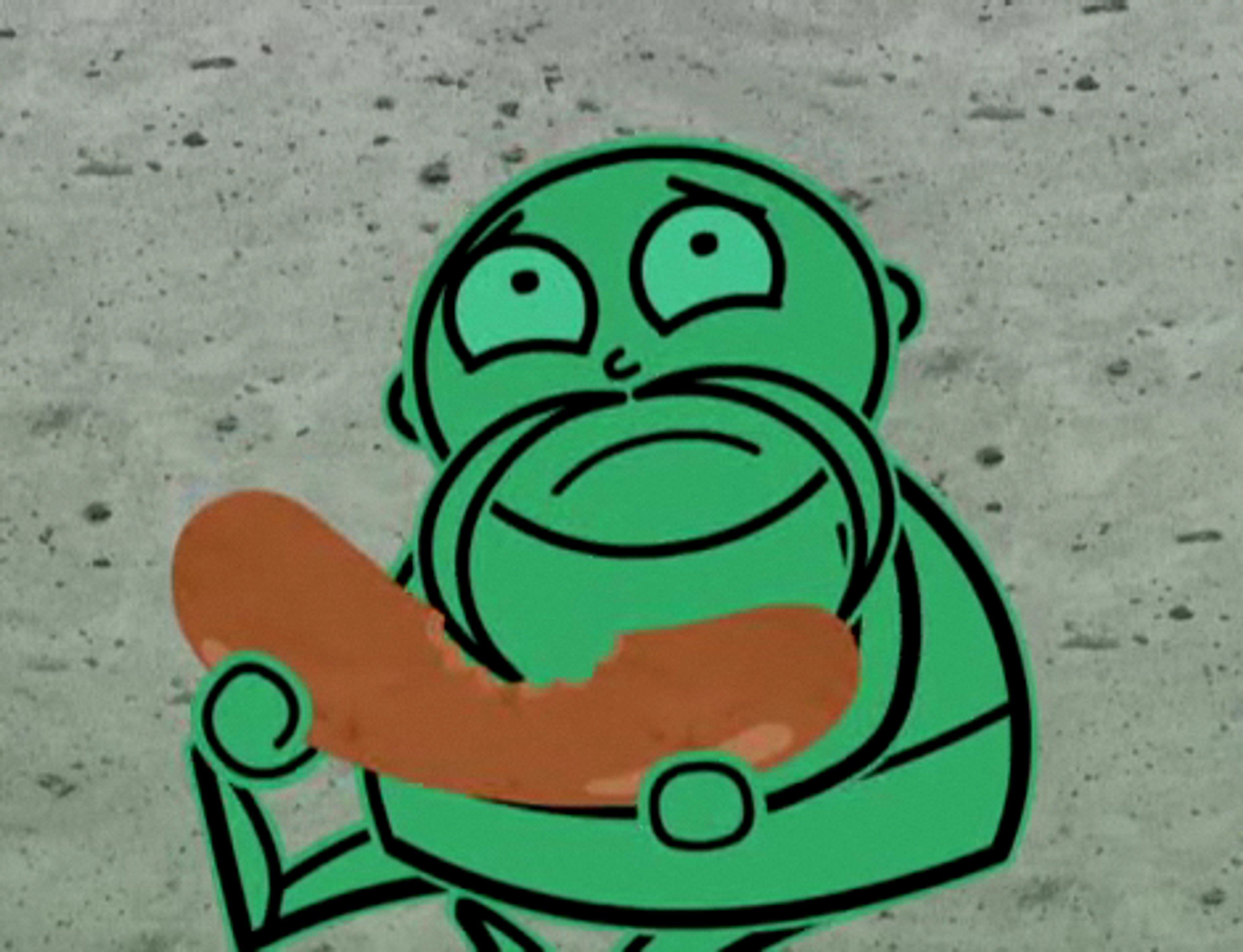 A small, green, elderly-looking cartoon character sitting in a miniature chair or furniture piece.